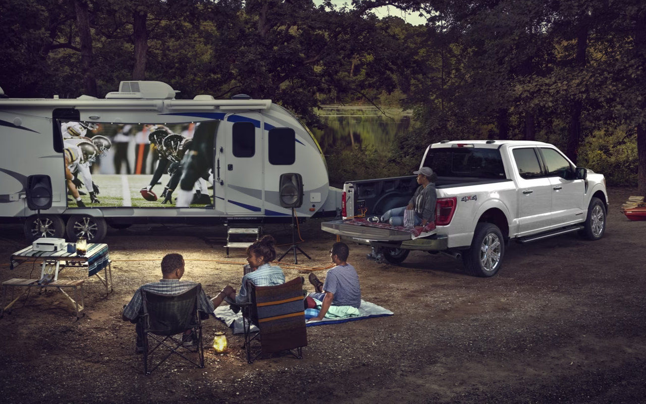 Vue arrière du Ford F-150 avec boite ouverte et équipement de camping avec famille qui écoute le football