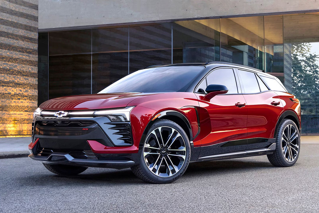 Vue 3/4 avant et latérale du Chevrolet Blazer EV 2025 stationné devant batîment publique avec phares allumées