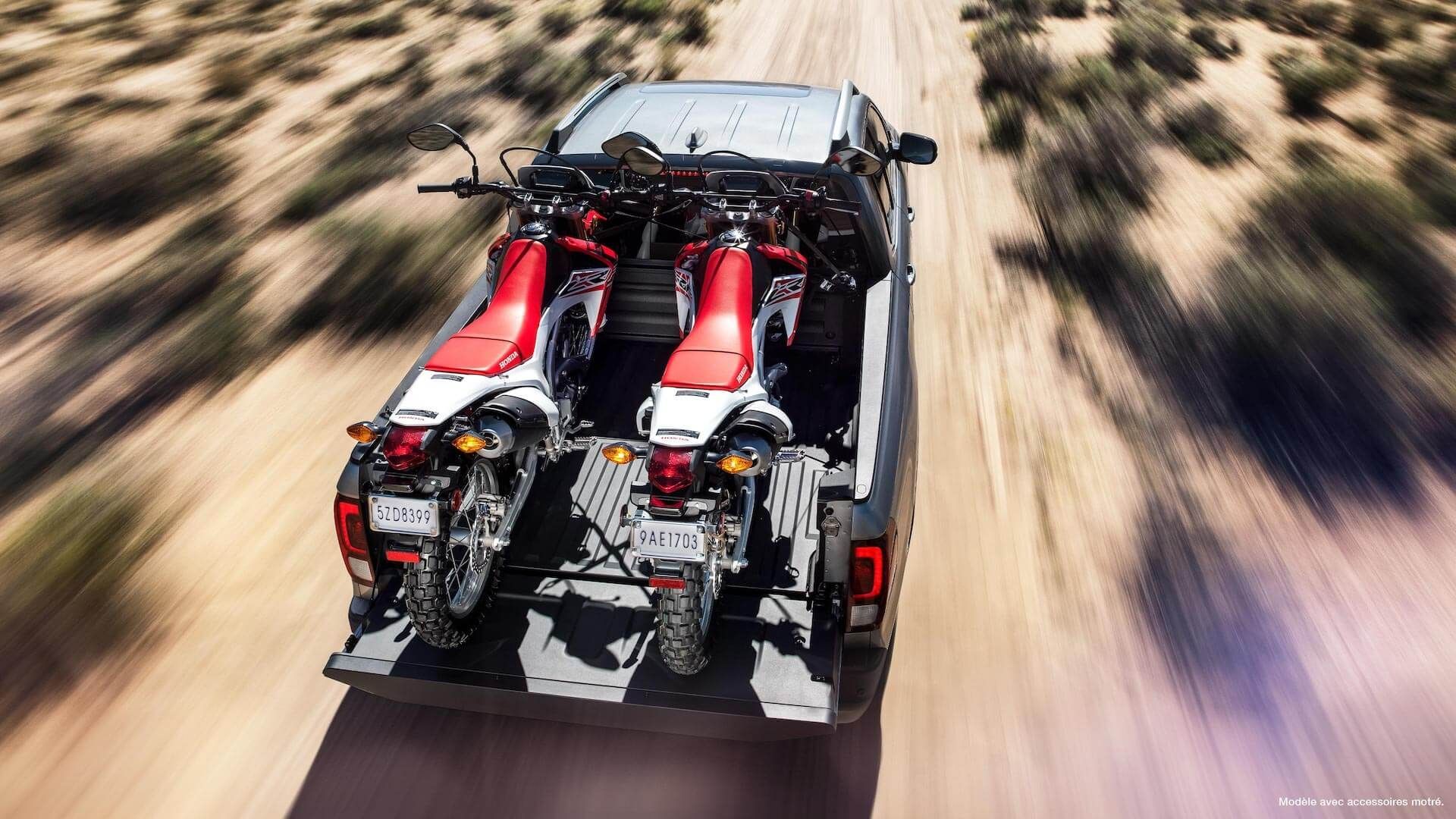 La Honda Ridgeline 2021 remorquant deux motocross Honda sur la route d'un désert