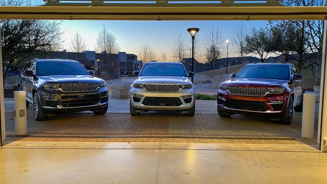 vue d'un trio de Jeep Grand Cherokee 2023 devant une porte de garage ouverte