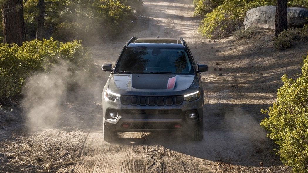 Vue avant du Jeep Compass 2025 roulant sur une piste en nature.