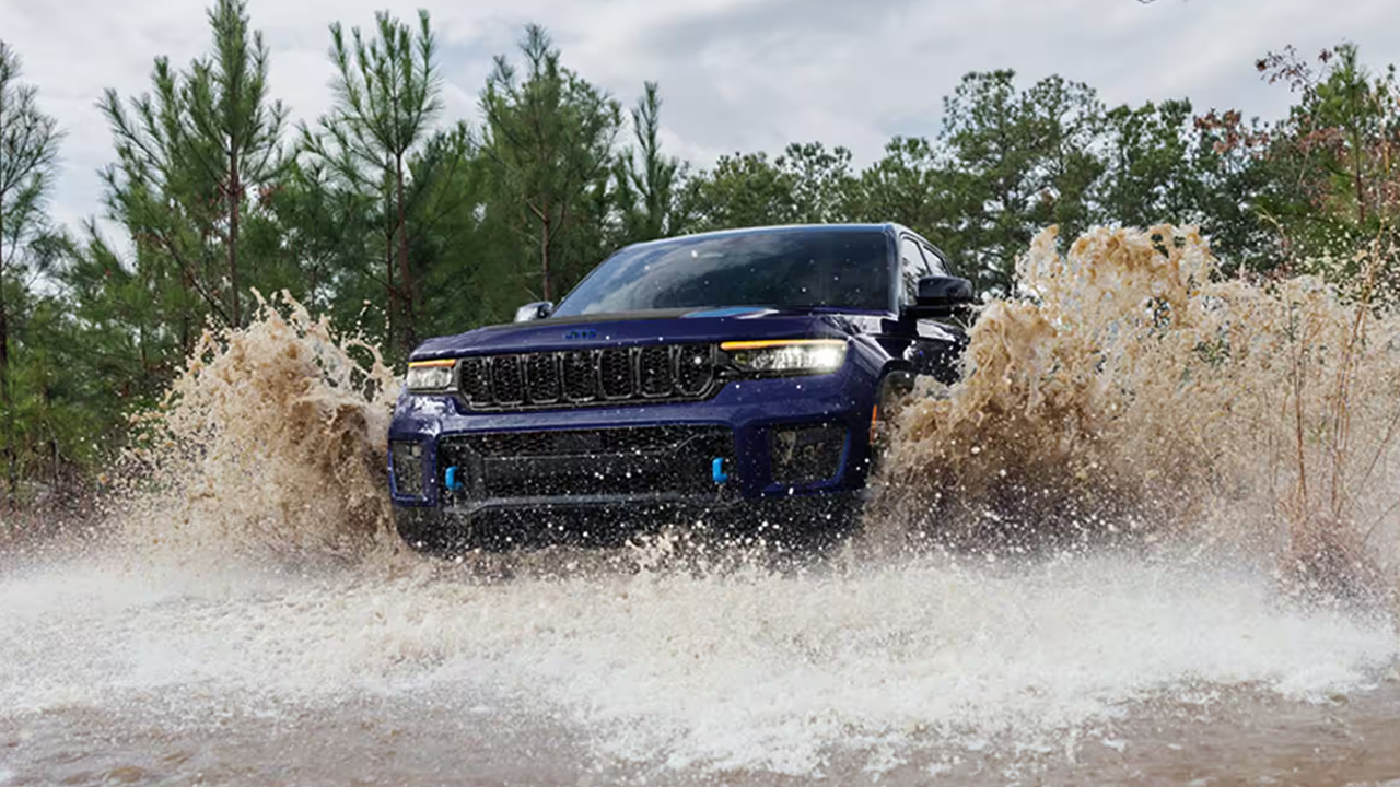 Vue 3/4 avant et latérale du Jeep Grand Cherokee, traversant une marre d'eau