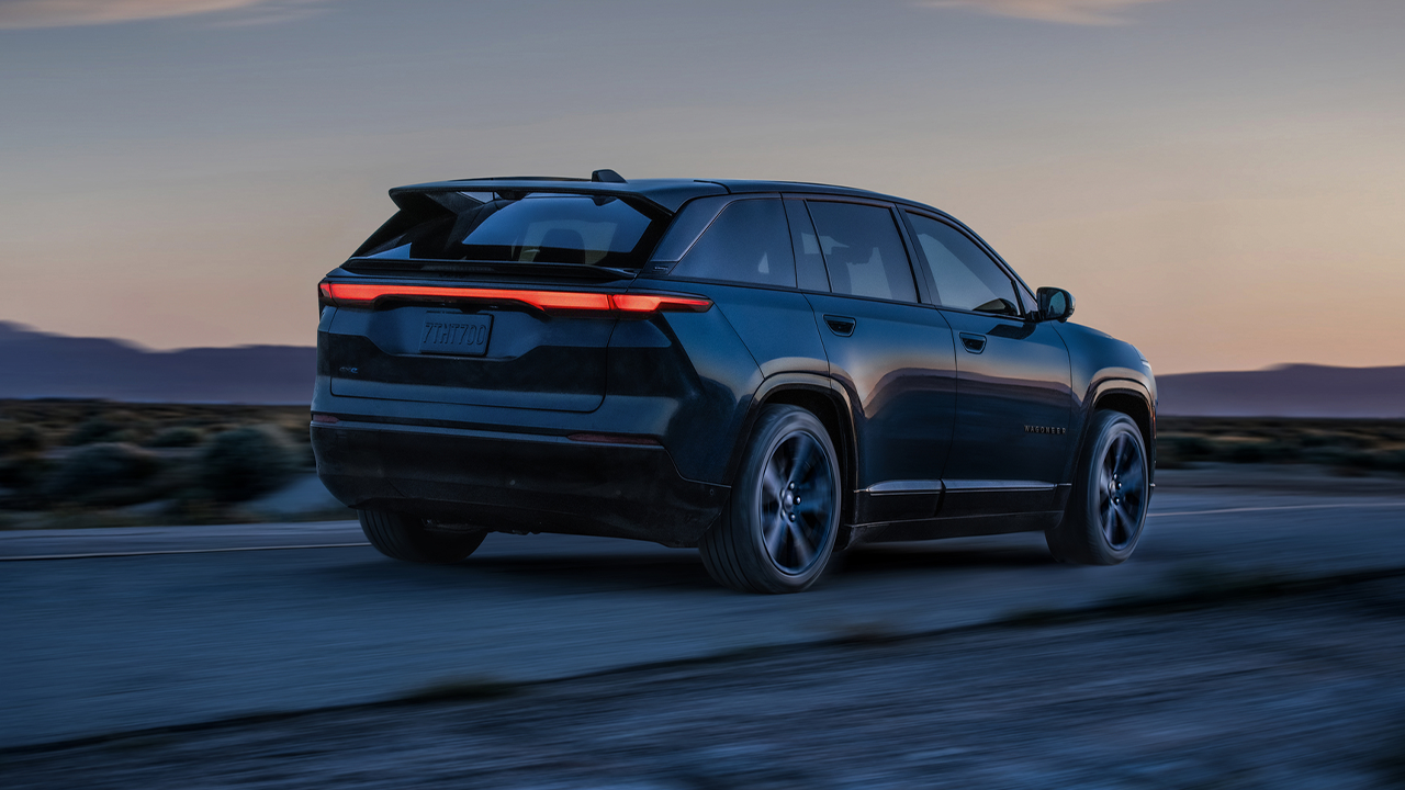 Vue arrière du Jeep Wagoneer S électrique 2025 sur route en pleine puissance au coucher de soleil