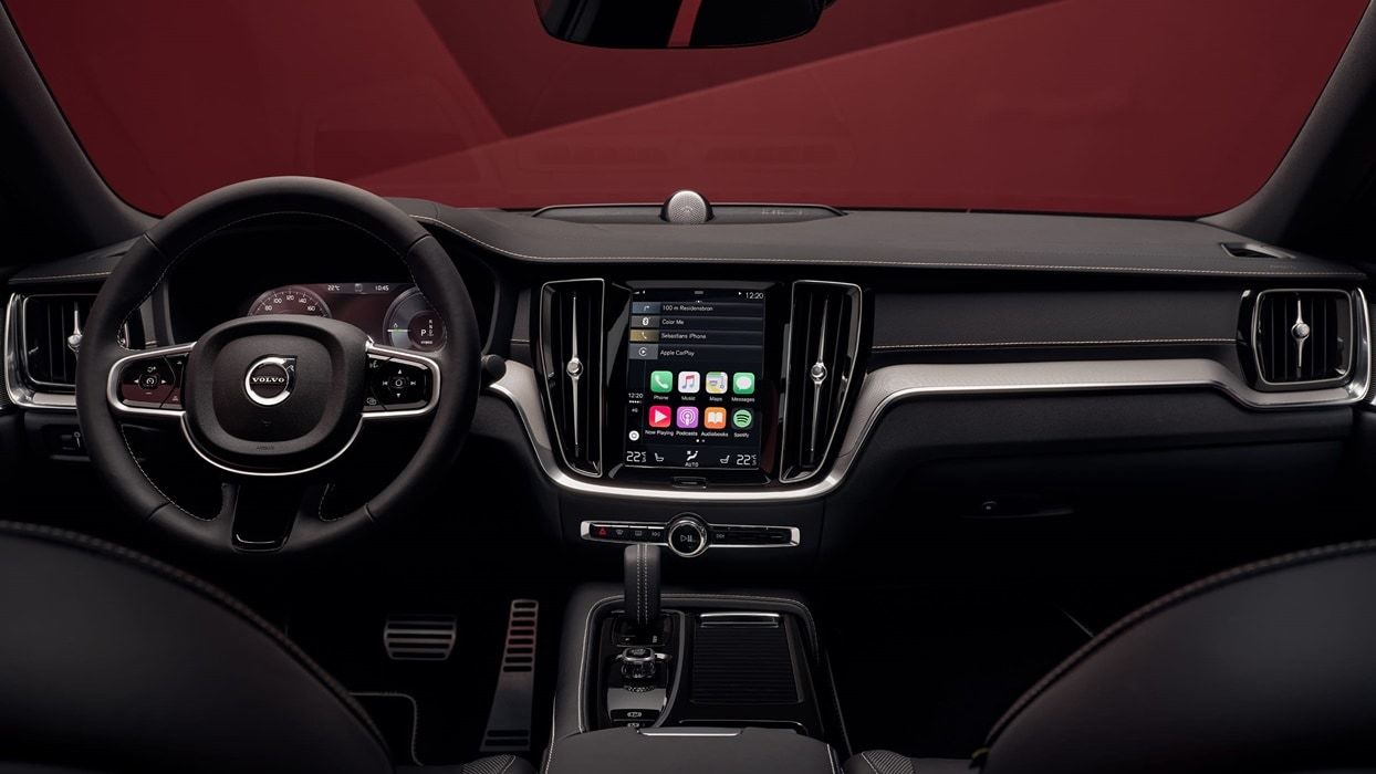 Image agrandit de l'intérieur d'une voiture volvo où l'on aperçoit le volant et l'écran tactile de la voiture ainsi que les applications