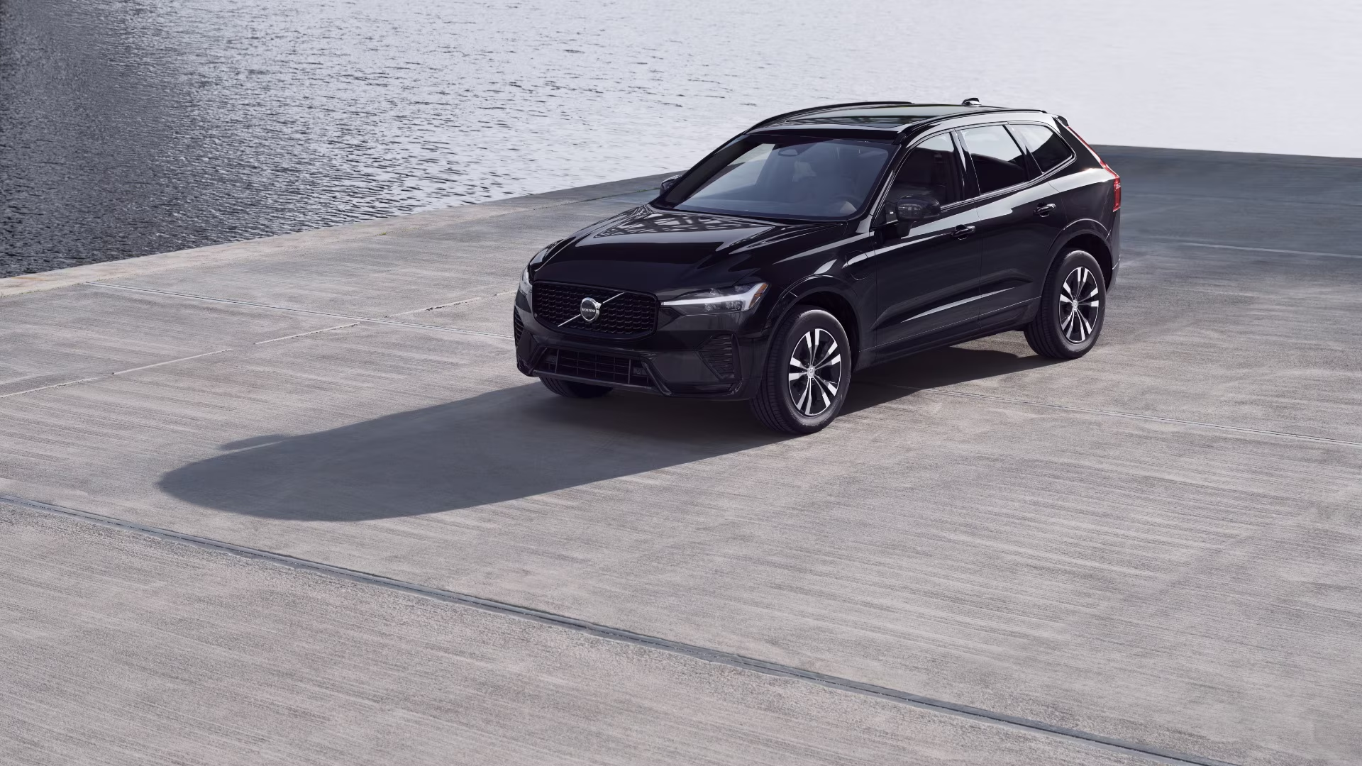 Volvo XC60 T8 hybride rechargeable noir stationné devant le bord de l'eau