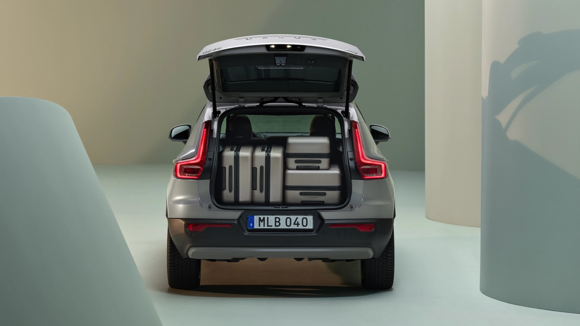 2025 Volvo XC40, rear view, open trunk, spacious cargo area, loaded with suitcases, practical design, premium compact SUV, ideal for travel.