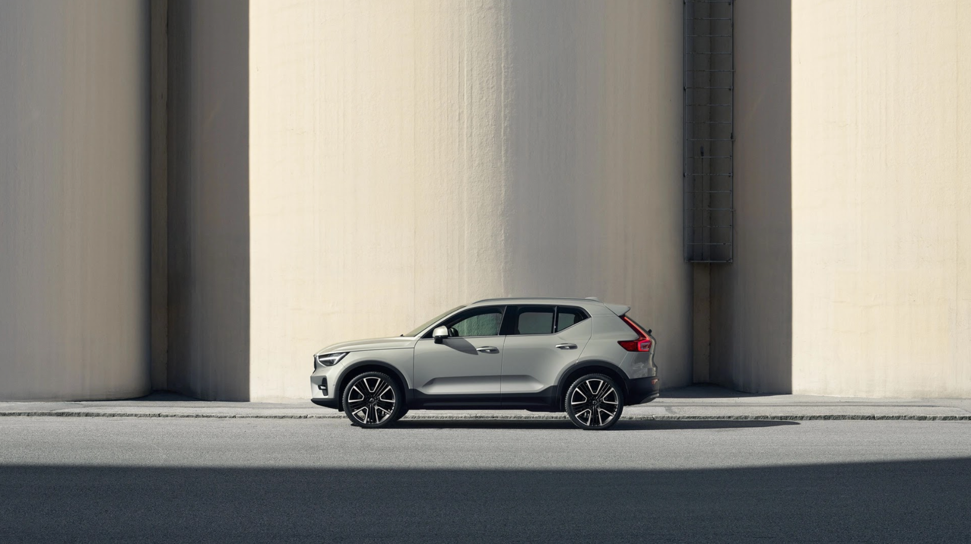 2025 Volvo XC40, side profile, urban setting, minimalist architecture, modern design, compact SUV, Scandinavian style, city-friendly vehicle.