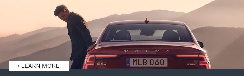 red 2021 volvo s60 vehicle seen from behind with a person leaning on it
