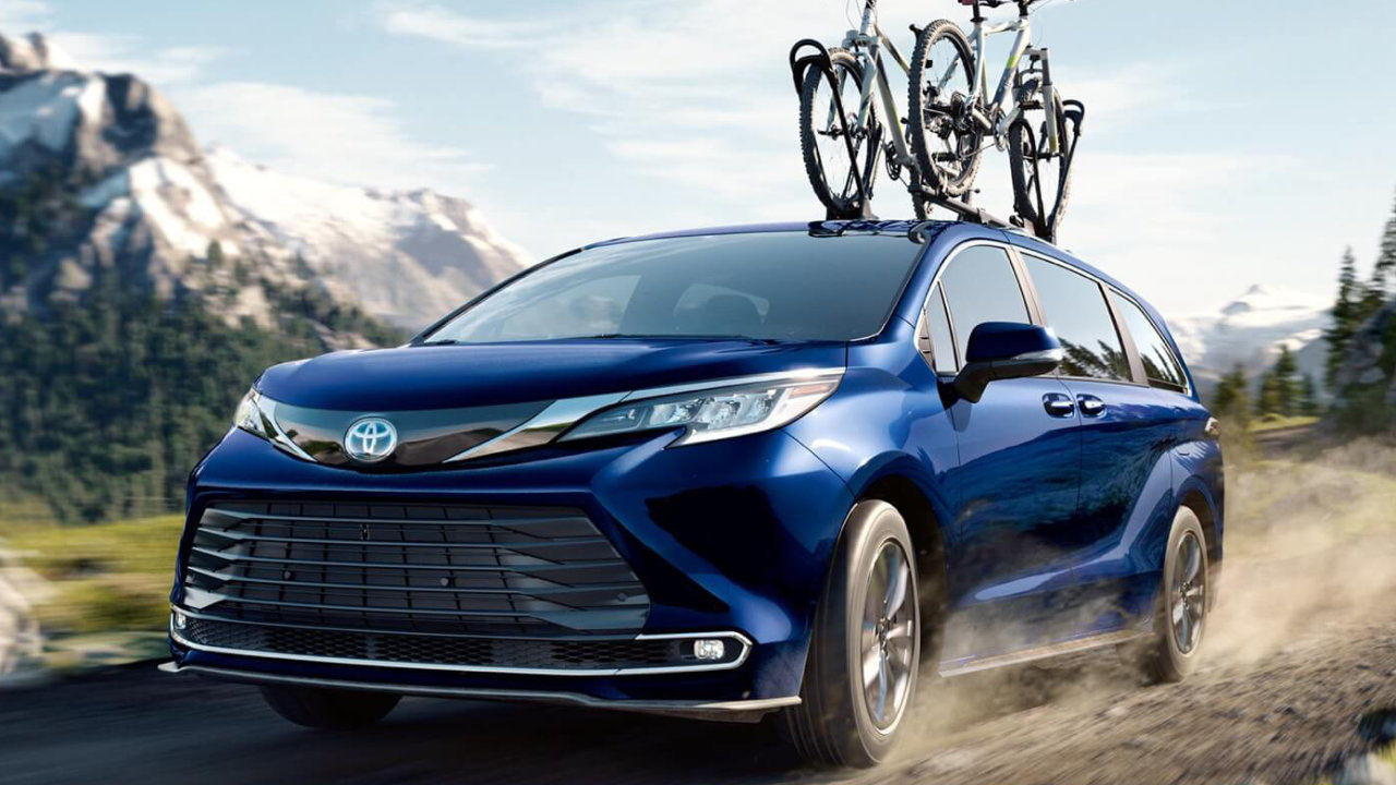 front side view of a 2022 Toyota Sienna carrying bikes on a country road