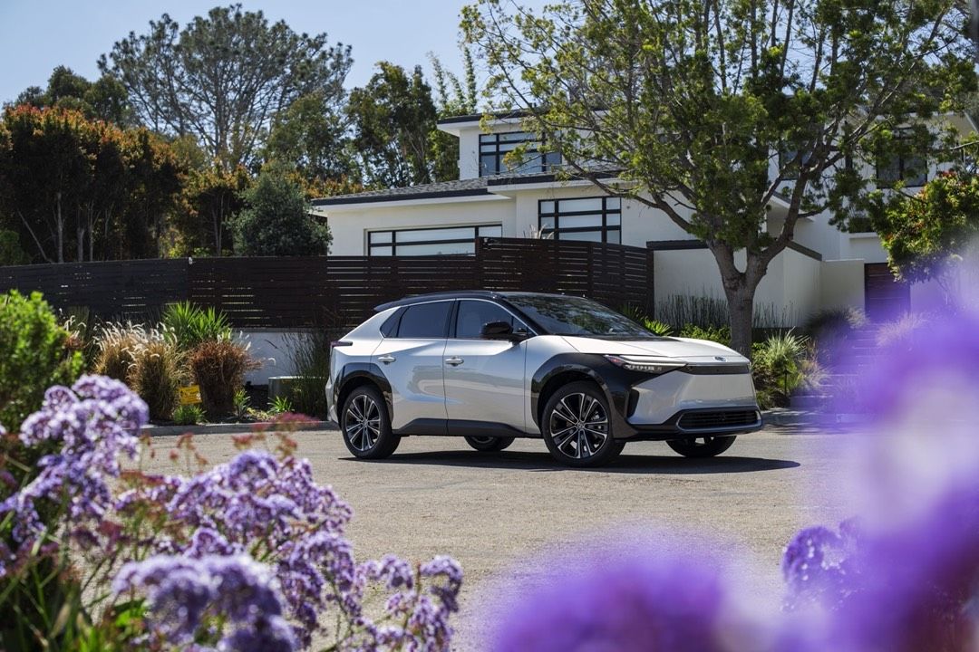 front side view of a 2023 Toyota bZ4X in front of a house with flowerswww