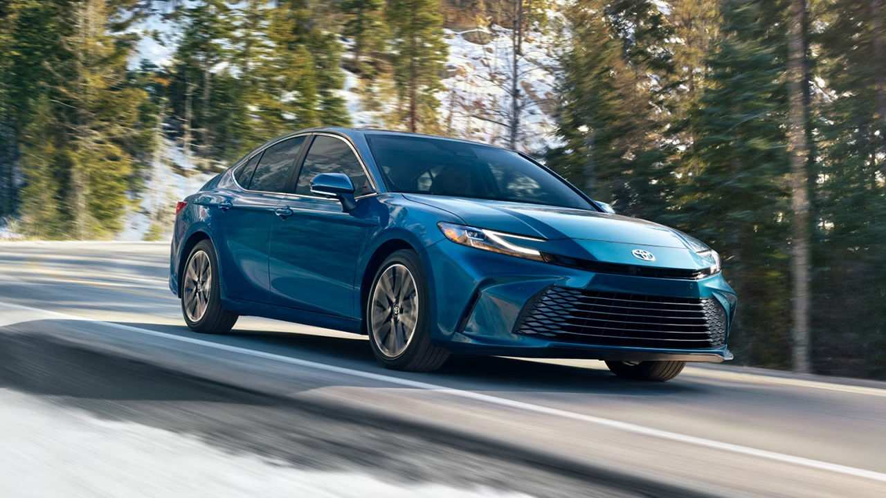 3/4 front and side view of the Toyota Camry Hybrid 2025 on a snow-covered mountain road at full power.