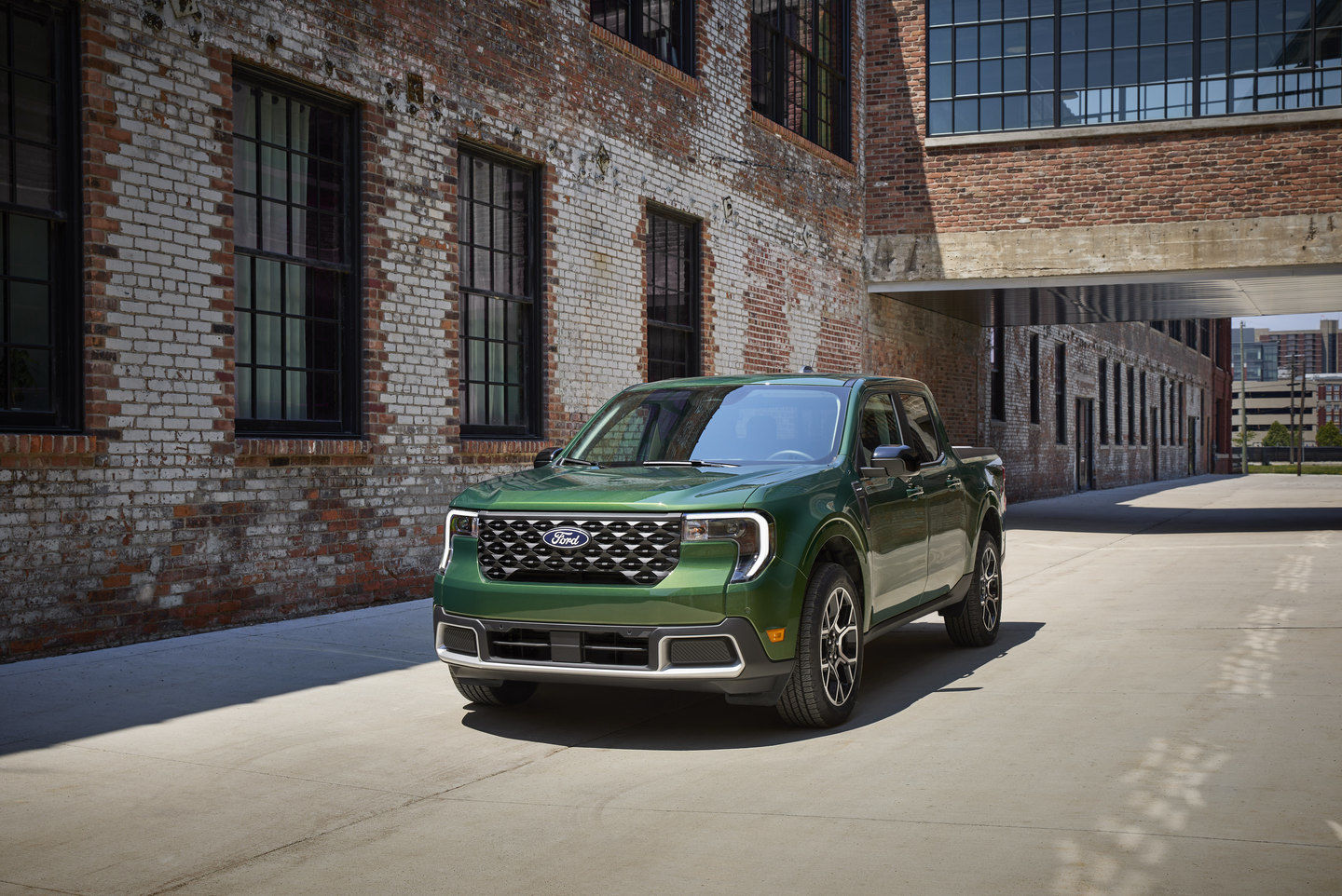 Green Ford Truck driving by weathered brick buildings