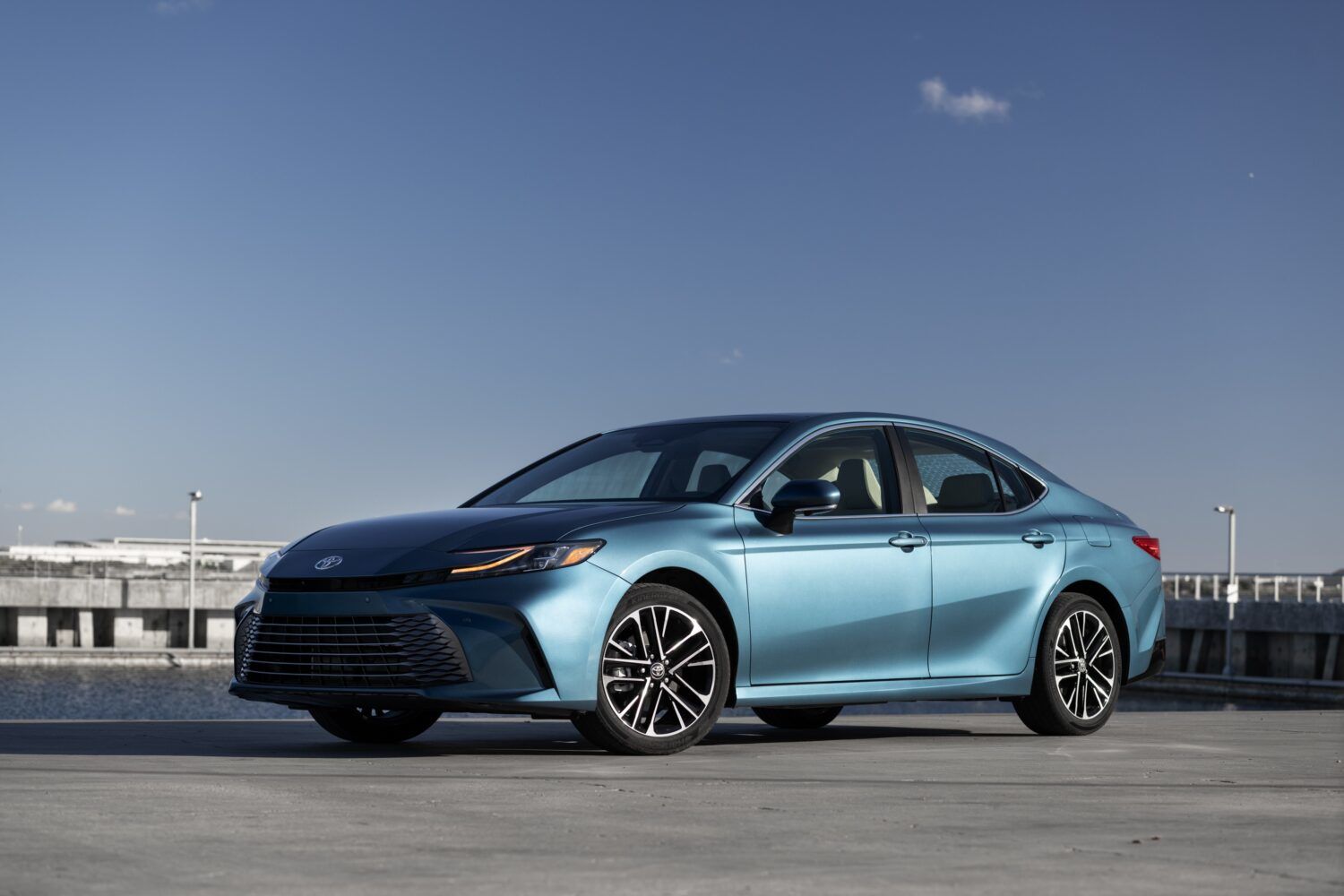 2025 Toyota Camry Hybrid - Teal car driving along river 