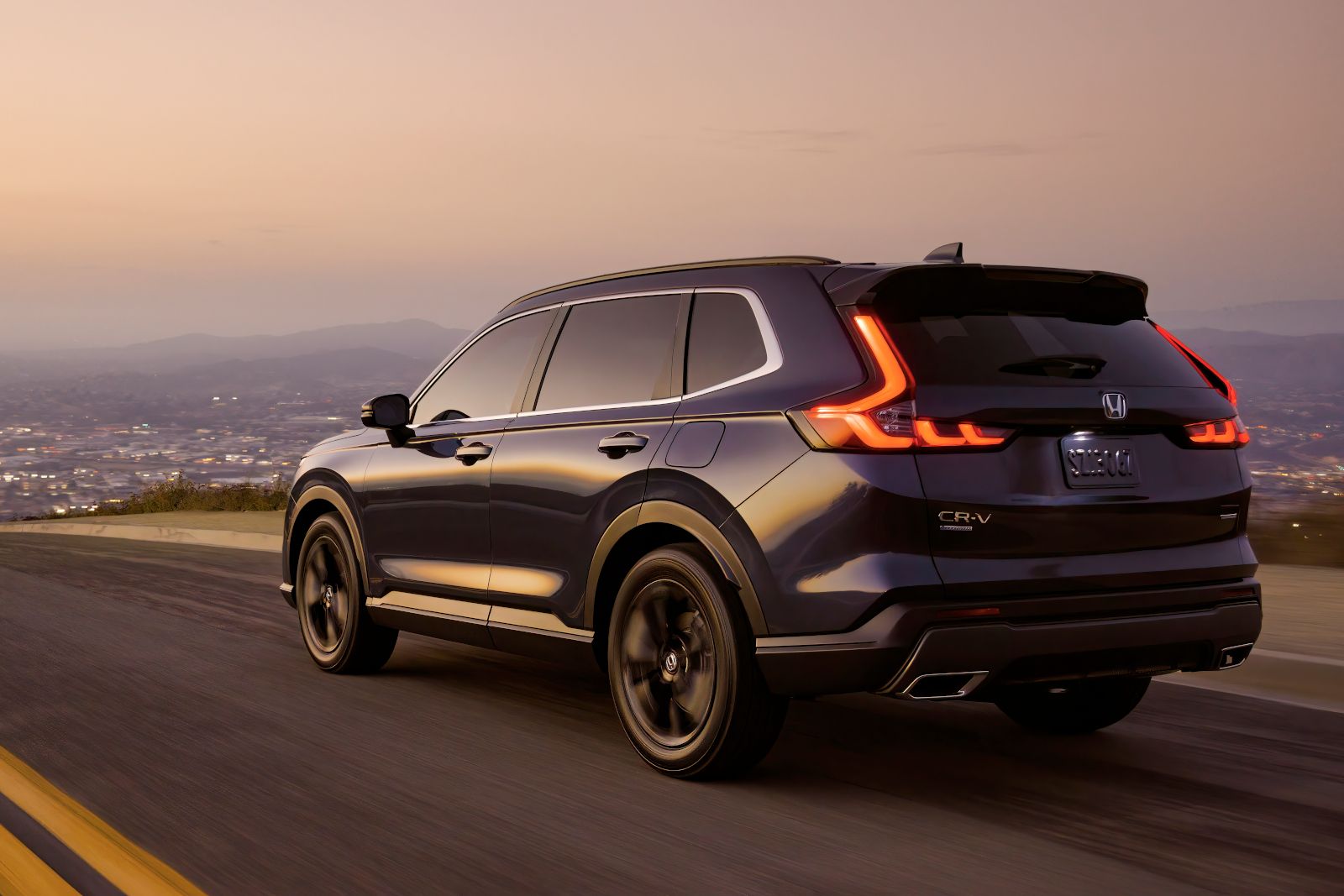 2026 Honda CR-V - Rear three-quarter view of a dark blue Honda CR-V driving at dusk - Orangeville Honda - Honda car dealership in Orangeville, Ontario
