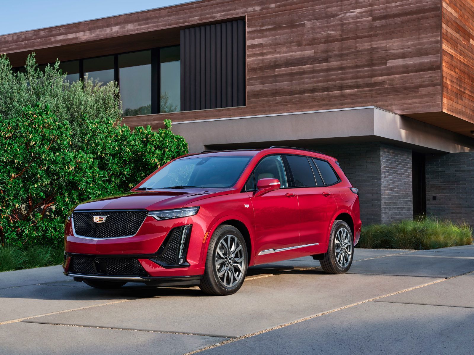 2025 Cadillac XT6 A red 2025 Cadillac XT6 parked in the driveway of a modern home - Applewood Cadillac - Cadillac car dealership in Mississauga, Ontario