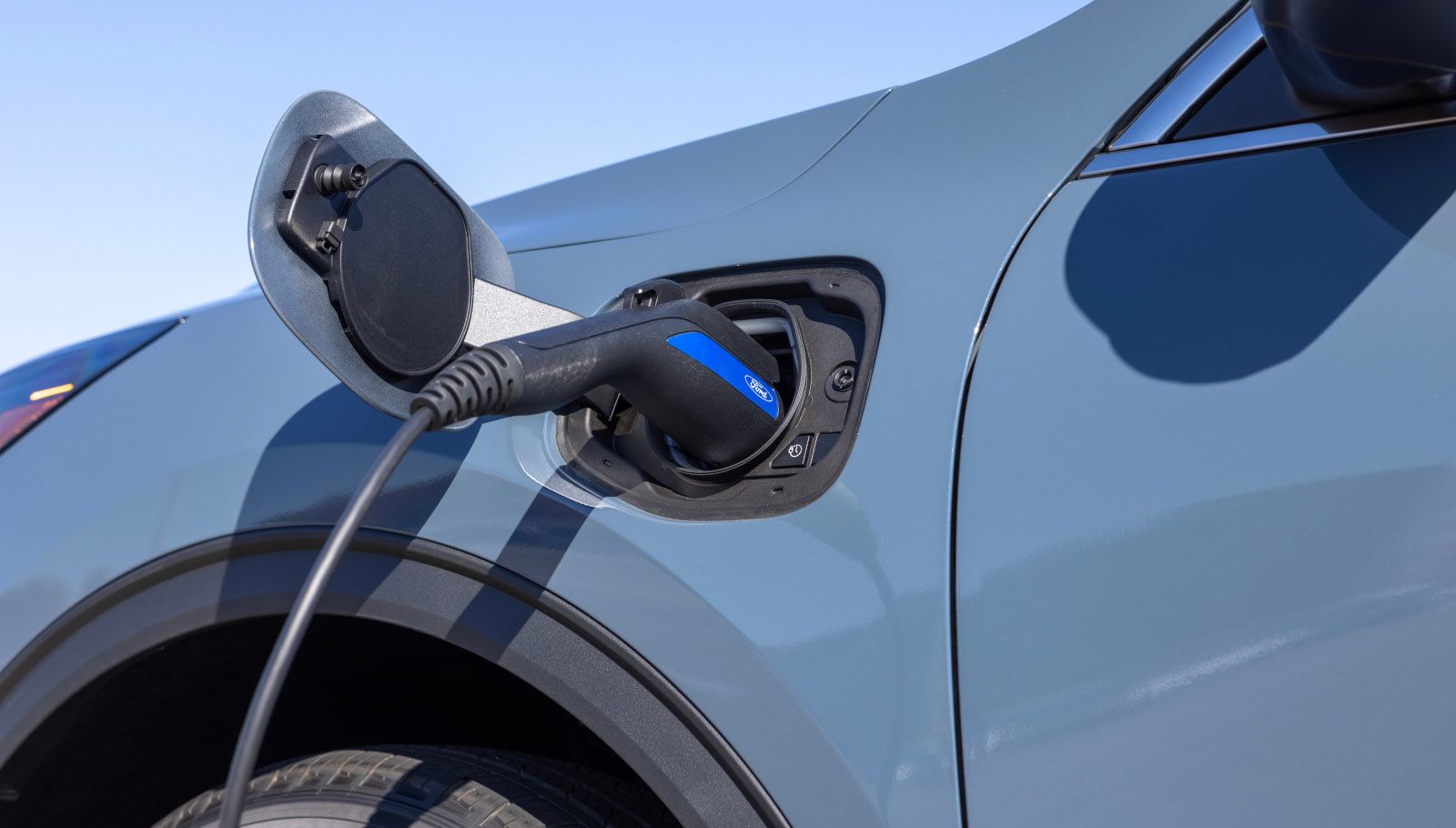 2025 Ford Escape Plug-In Hybrid - a close-up of a charger plugged into the port of a light blue 2025 Ford Escape - Mayfield Ford - Ford car dealership in Brampton, Ontario