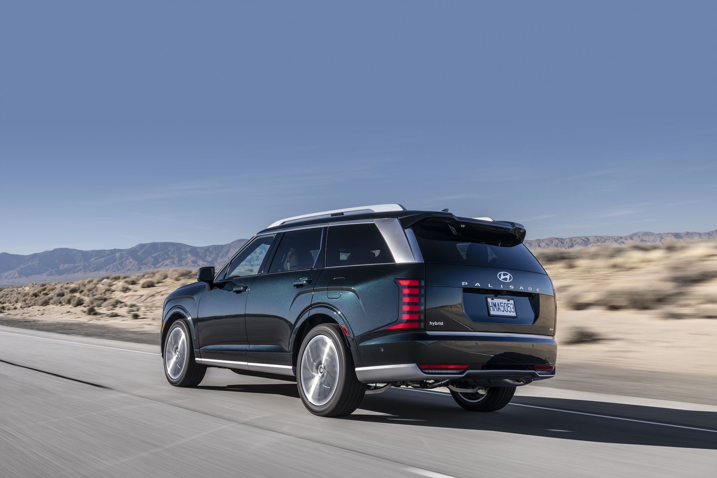 2026 Hyundai Palisade - rear-quarter view of a dark green 2026 Hyundai Palisade Hybrid Calligraphy driving on a highway - Woodstock Hyundai - Hyundai car dealership in Woodstock, ON