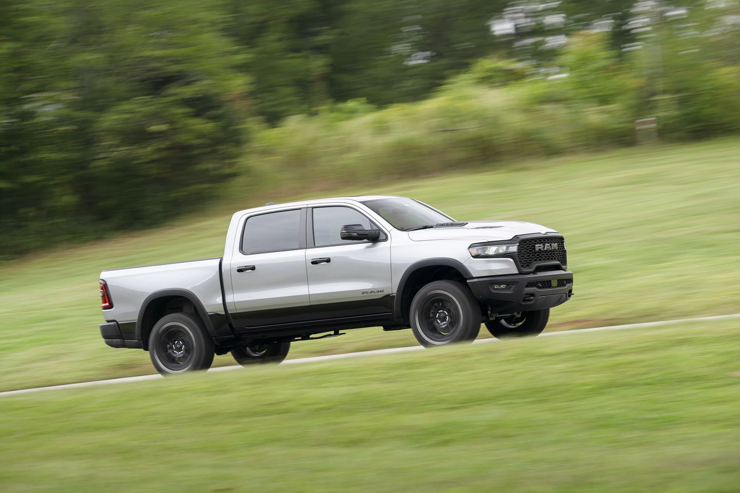 2025 Ram 1500 Rebel a silver truck driving on a grassy incline - Cooksville Dodge - Ram car dealership in Mississauga, Ontario