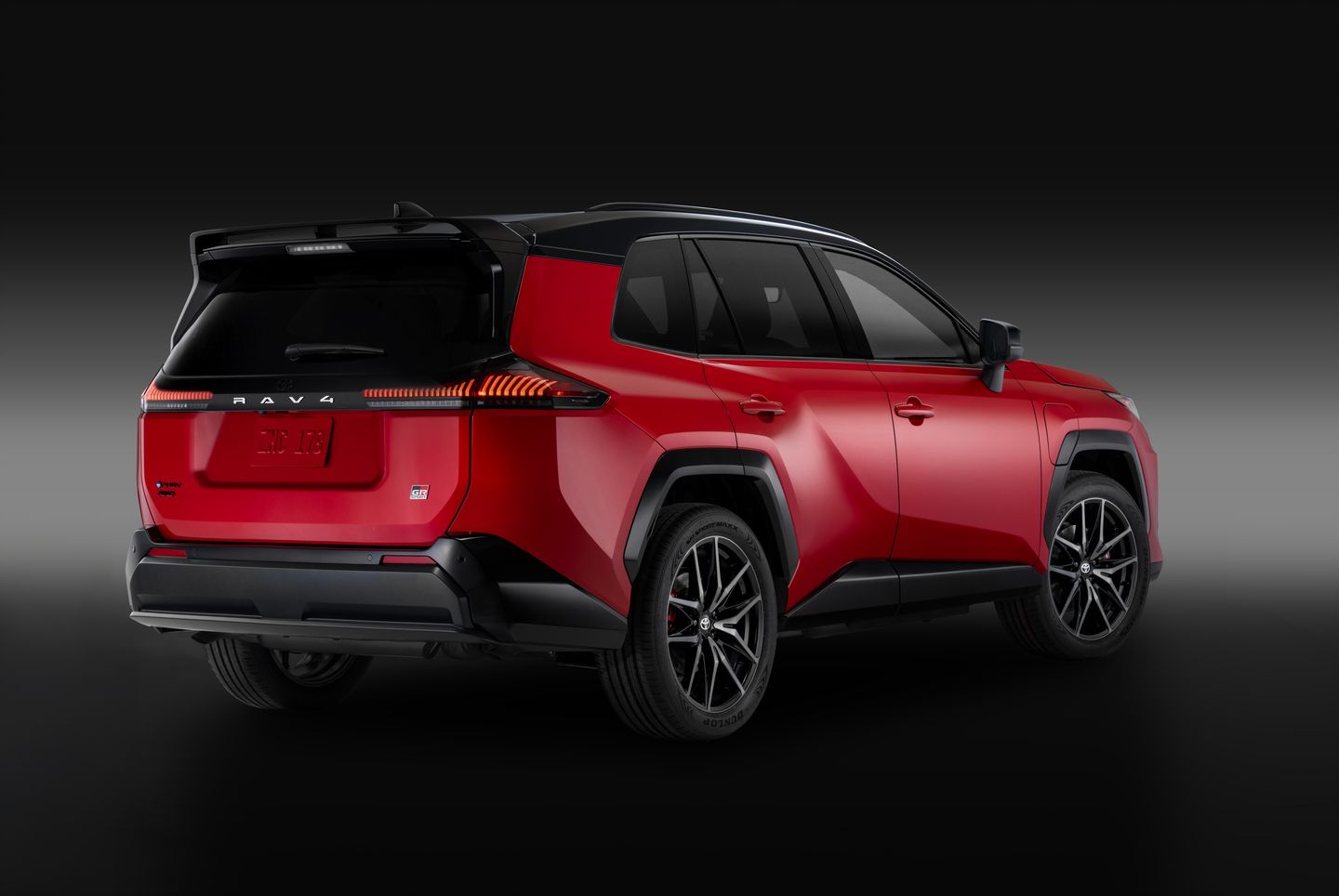 2026 Toyota RAV4 - rear-quarter view of a red 2026 Toyota RAV4 in a studio with a dark background - Georgetown Toyota - Toyota car dealership in Georgetown, Ontario