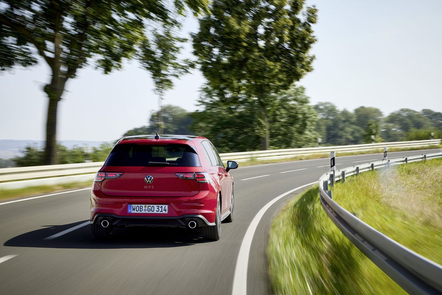 2025 Volkswagen Golf GTI - Rear view of a red 2025 Volkswagen Golf GTI driving on a winding road - Volkswagen MidTown - Volkswagen car dealership in Toronto, Ontario