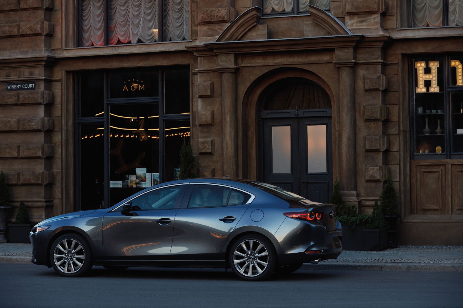 2020 Mazda 3 - a dark grey 2020 Mazda 3 parked in front of a city building - AutoPark Barrie pre-owned car dealer in Innisfil, Ontario