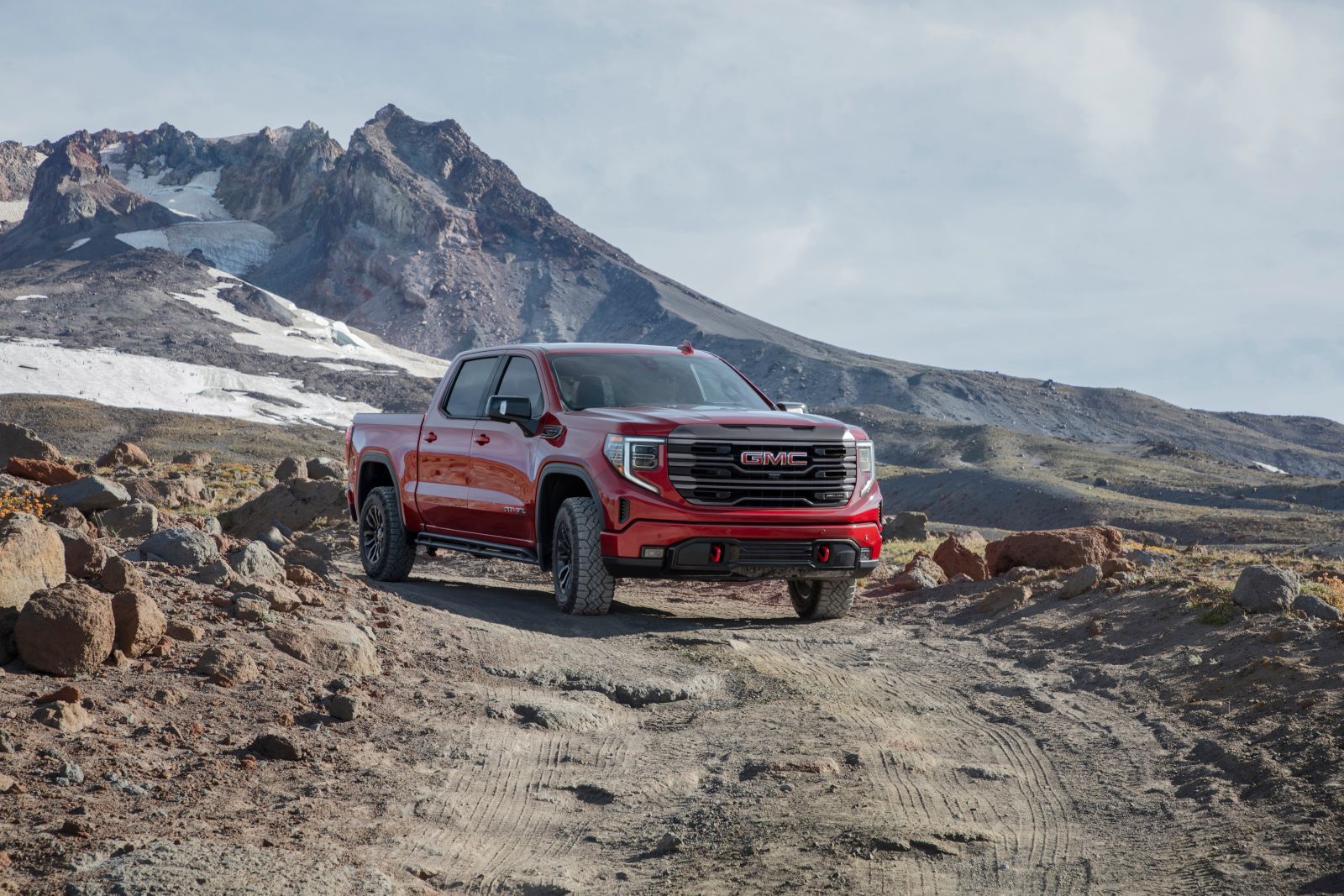 2025 GMC Sierra 1500 AT4X - front view of a red 2025 GMC Sierra 1500 AT4X on a dirt path with mountains in the background - Applewood Chevrolet Buick GMC - GMC car dealership in Mississauga, Ontario