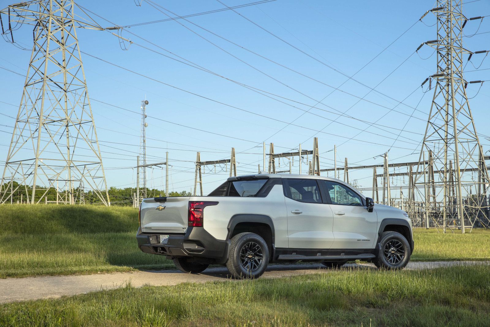 2025 Chevrolet Silverado EV rear three-quarter view of a white model parked on a dirt path - City Chevrolet Buick GMC - Chevrolet car dealership in Toronto, Ontario