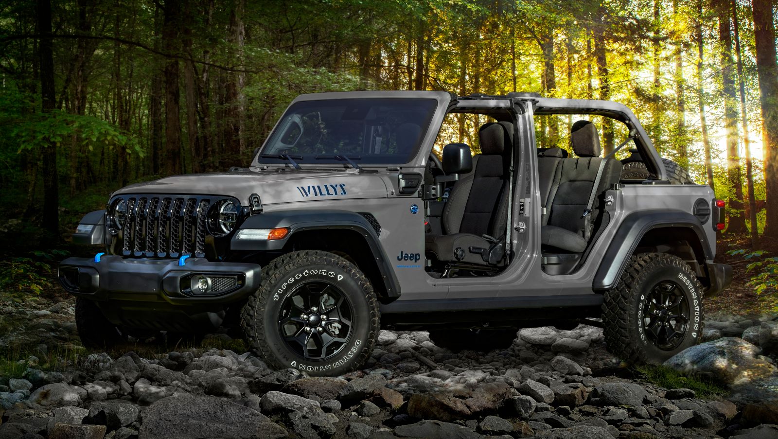 2025 Jeep Wrangler Willys 4xe - a grey 2025 Jeep Wrangler Willys 4xe with its doors and top off, parked on rocks in a forest setting - Cooksville Dodge Chrysler Jeep Ram - Jeep car dealership in Mississauga, Ontario