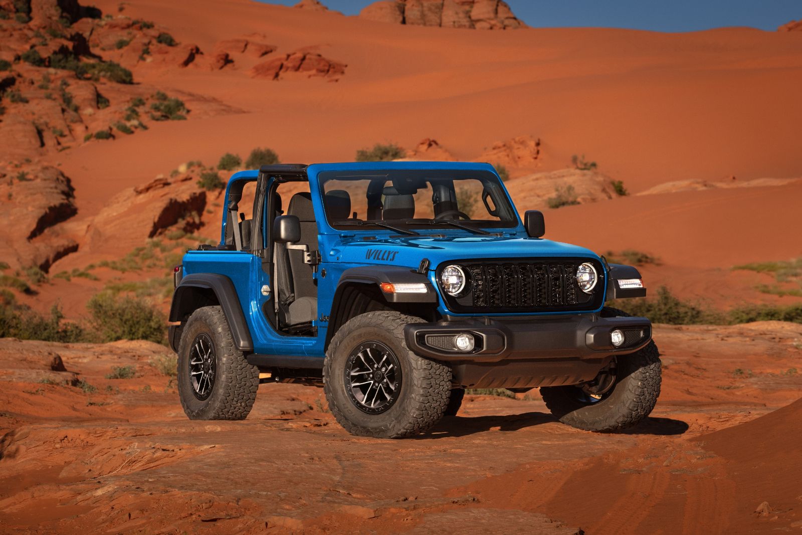 2025 Jeep Wrangler Willys - front view of a blue two-door 2025 Jeep Wrangler Willys with its doors off, parked in a red rock desert landscape - Cooksville Dodge Chrysler Jeep Ram - Jeep car dealership in Mississauga, Ontario