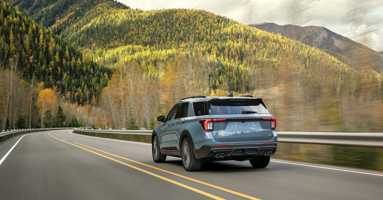 2025 Ford Explorer ST - rear view of the blue 2025 Ford Explorer ST driving on a scenic mountain highway - Bayfield Ford - Ford car dealership in Barrie, ON