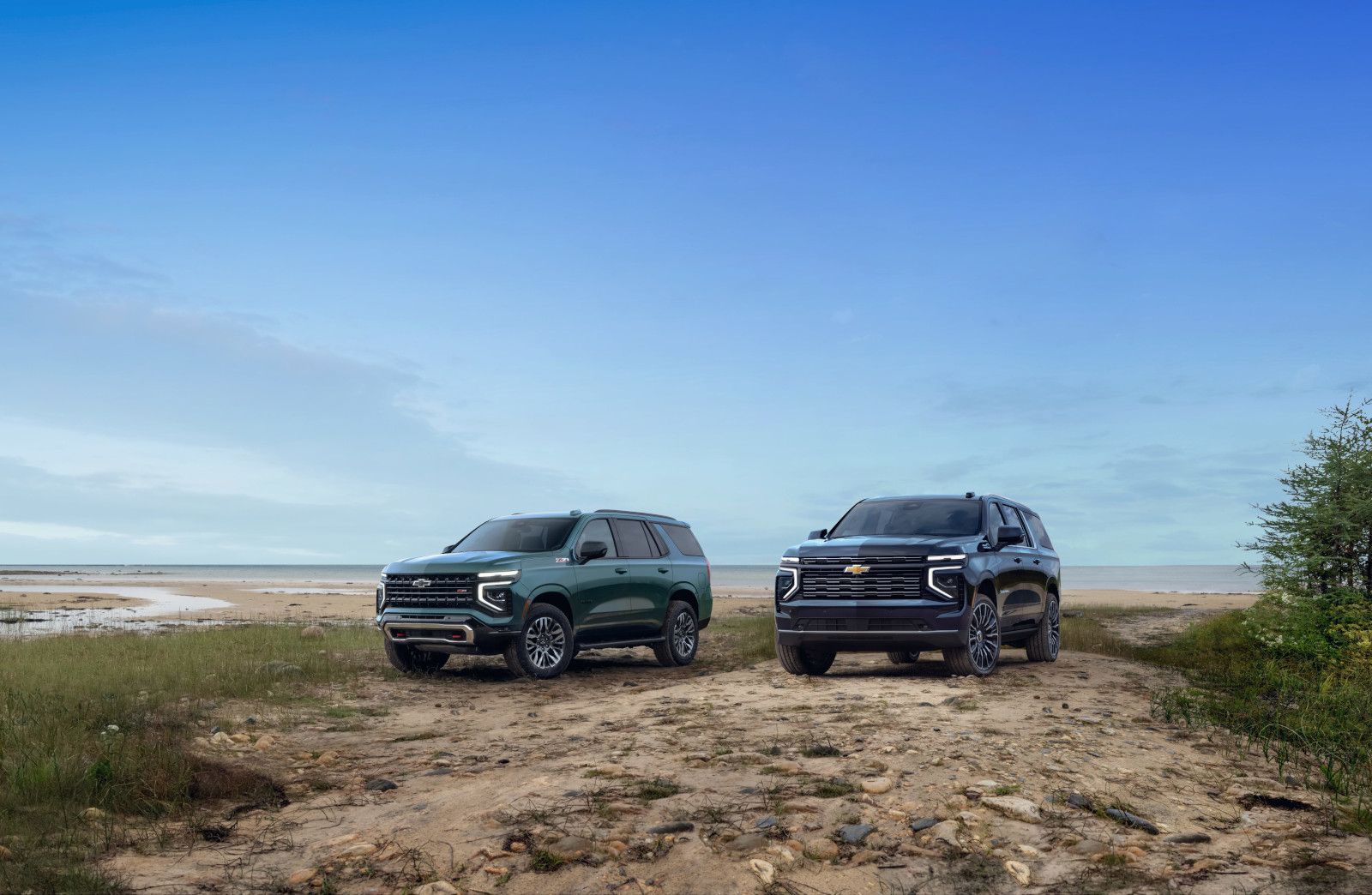 2025 Chevrolet Tahoe and Suburban - a green 2025 Chevrolet Tahoe and a black 2025 Chevrolet Suburban parked on a sandy beach path - City Chevrolet Buick GMC - new car dealerships in Ontario