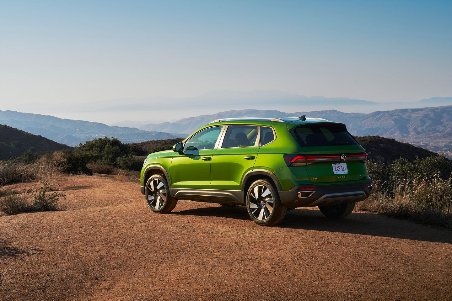 2025 Volkswagen Taos rear three-quarter view of a green Volkswagen Taos parked on a scenic mountain overlook - Humberview Volkswagen - new car dealerships in Ontario