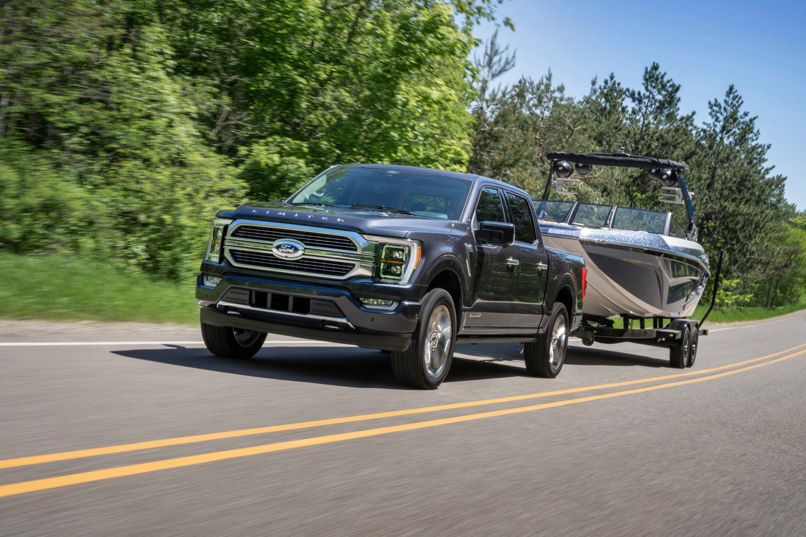 2025 Ford F-150 - a dark gray Limited model towing a boat on a highway - AutoPark Barrie - Pre-owned car dealership in Innisfil, Ontario