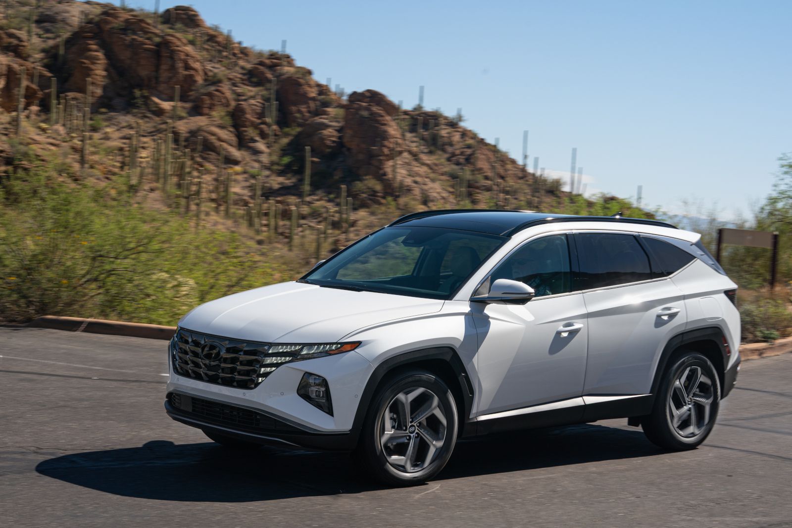 2023 Hyundai Tucson Hybrid - a white 2023 Hyundai Tucson Hybrid driving on a paved road - AutoPark Brampton - Pre-owned car dealership in Brampton, Ontario