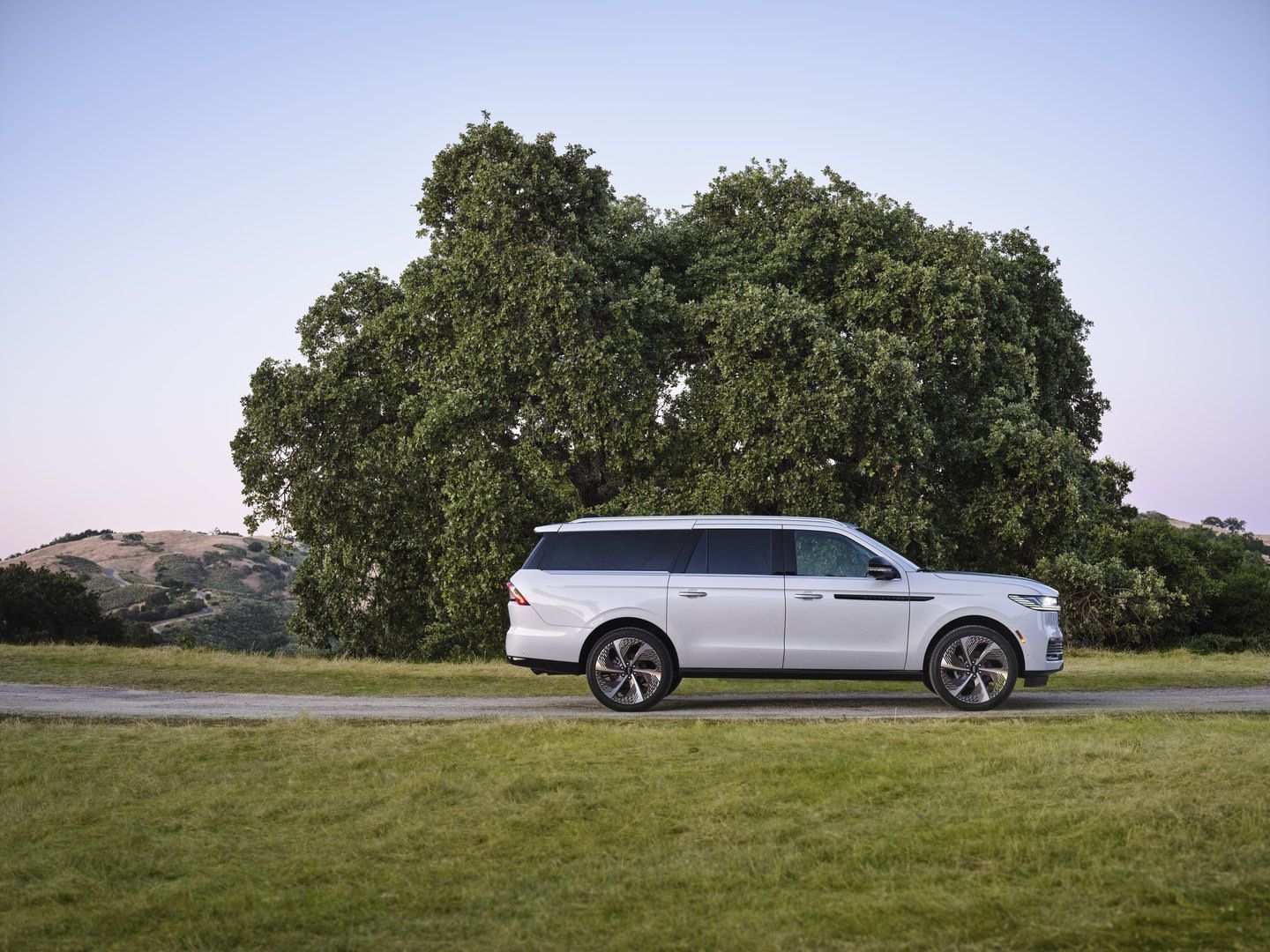 2025 Lincoln Navigator L - side profile of a white extended-wheelbase Lincoln Navigator L parked on a road in the countryside - Mayfield Lincoln - New car dealership in Brampton, Ontario
