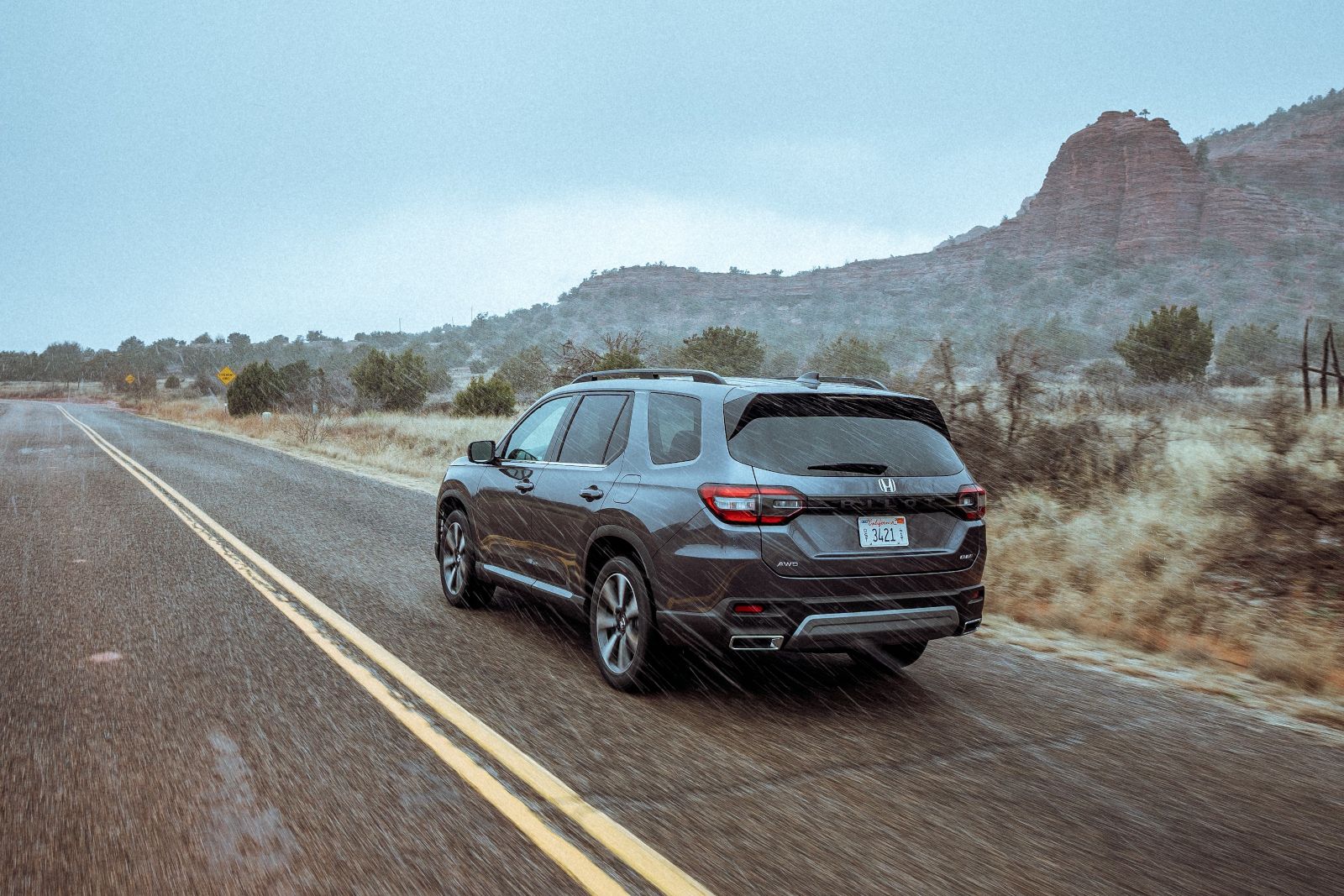 2025 Honda Pilot - a grey 2025 Honda Pilot driving on a winding road in the rain - Goderich Honda - New car dealership in Goderich, Ontario