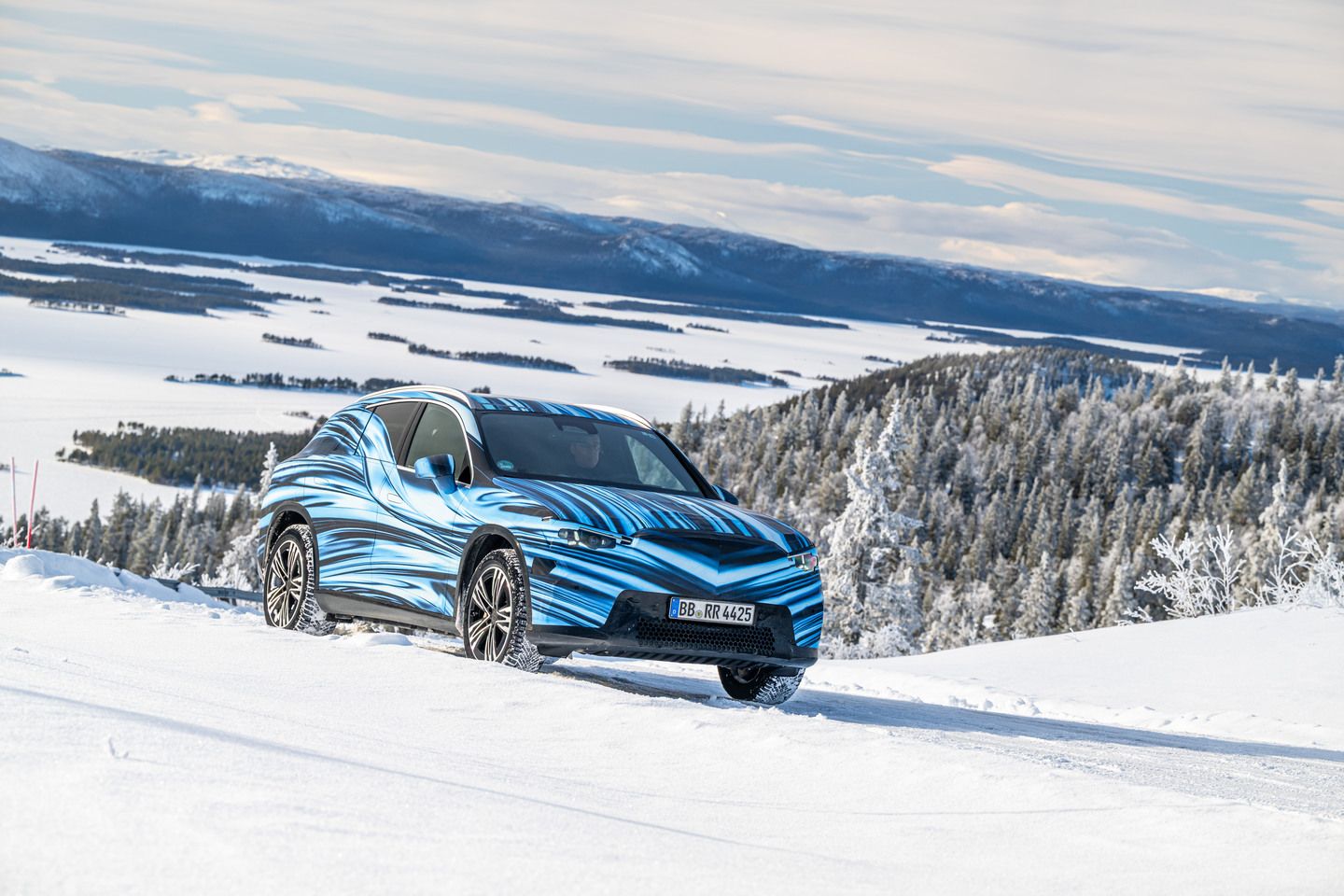 2025 Mercedes-Benz GLC EQ - a front three-quarter view of a blue-camouflaged 2025 Mercedes-Benz GLC EQ prototype in a snowy mountain landscape - Mercedes-Benz Brampton - New car dealership in Brampton, Ontario