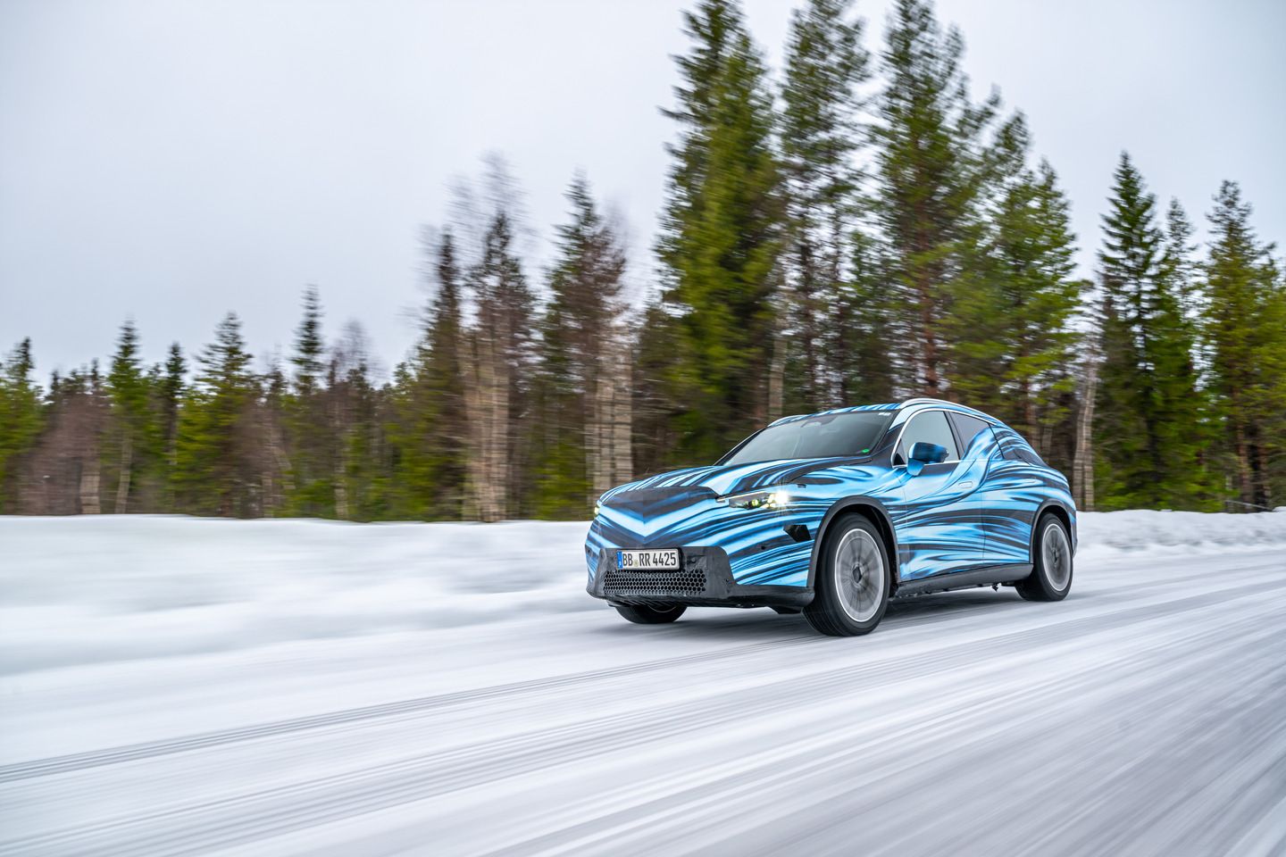 2025 Mercedes-Benz GLC EQ - a blue-camouflaged 2025 Mercedes-Benz GLC EQ prototype driving at speed on a snowy road - Mercedes-Benz Brampton - New car dealership in Brampton, Ontario