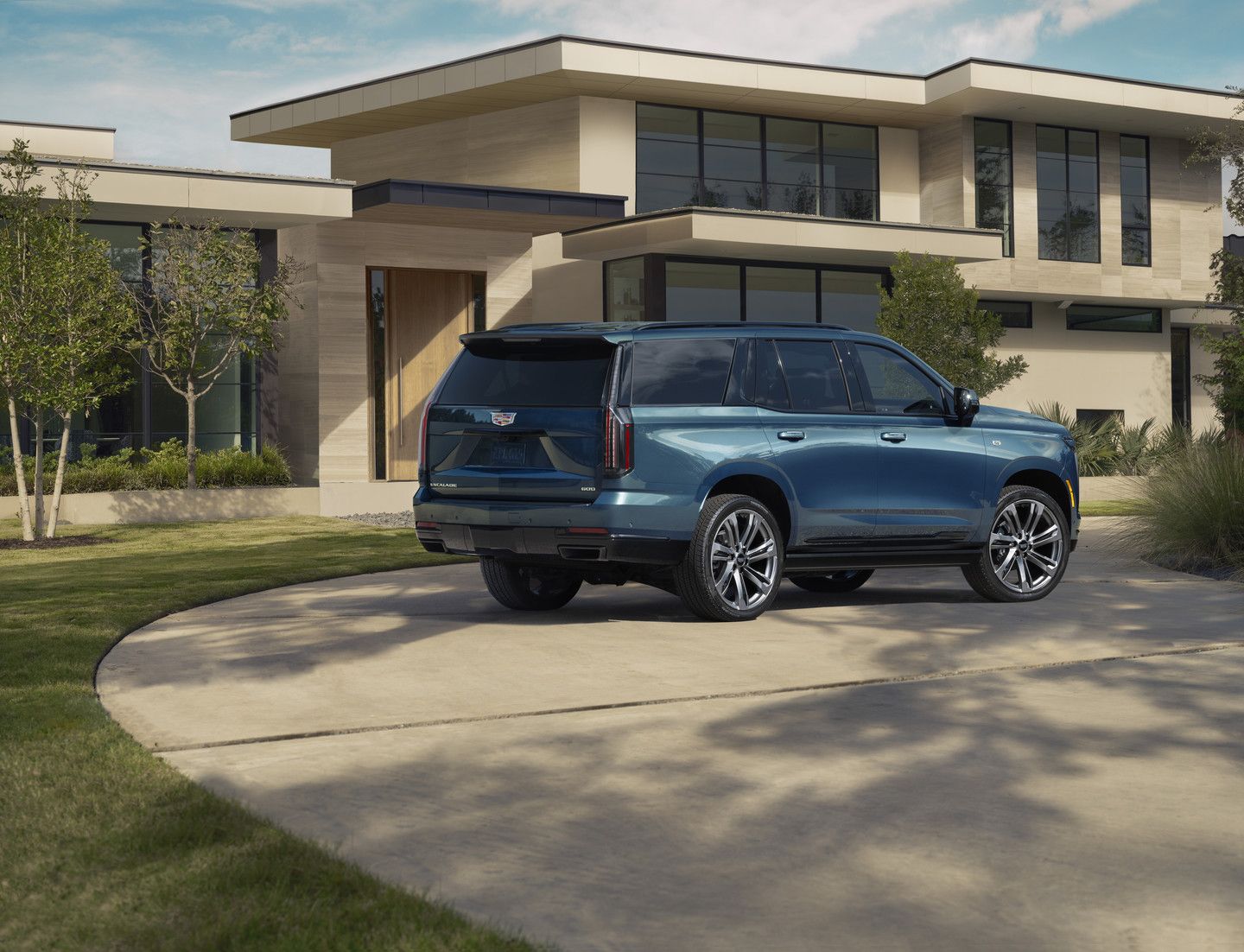 2026 Cadillac Escalade - Rear three-quarter view of a blue Cadillac Escalade parked in the driveway of a modern home - City Cadillac - Cadillac car dealership in Toronto, Ontario
