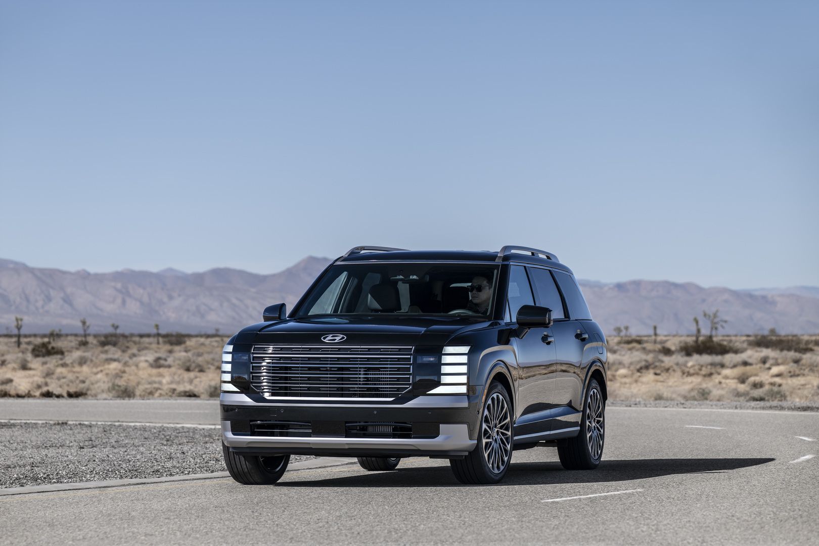 2026 Hyundai Palisade Hybrid - Front view of a dark green Palisade Hybrid on a winding desert road - Woodstock Hyundai - Hyundai car dealership in Woodstock, Ontario
