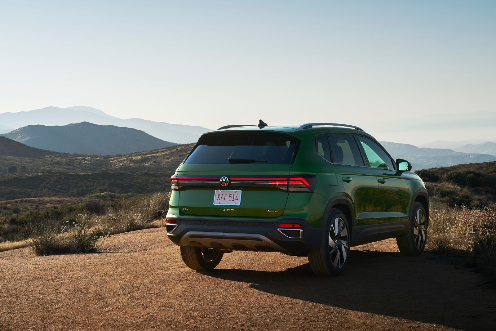 2026 Volkswagen Taos - Rear three-quarter view of a green 2026 Volkswagen Taos parked on a dirt road with mountains in the background - Humberview Volkswagen - New car dealership in Toronto, Ontario