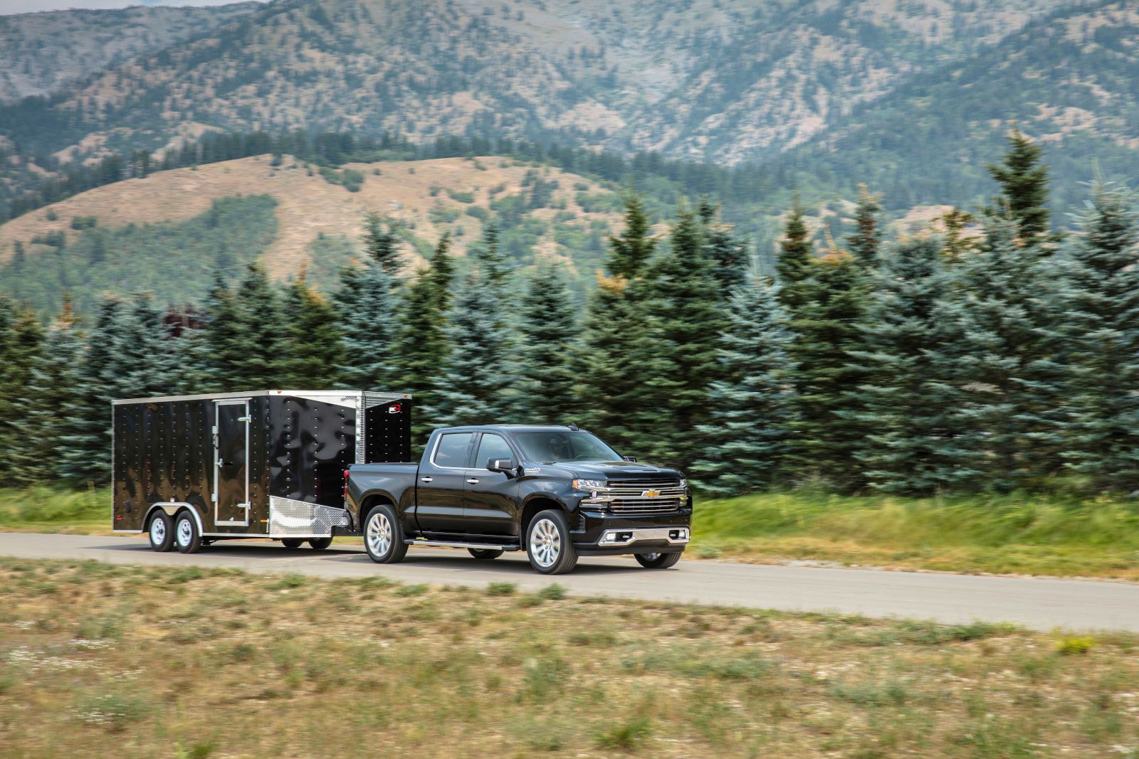 Chevrolet Silverado - a black Chevrolet Silverado towing a large enclosed trailer on a paved road - Autopark Brampton - Used car dealership in Brampton, Ontario