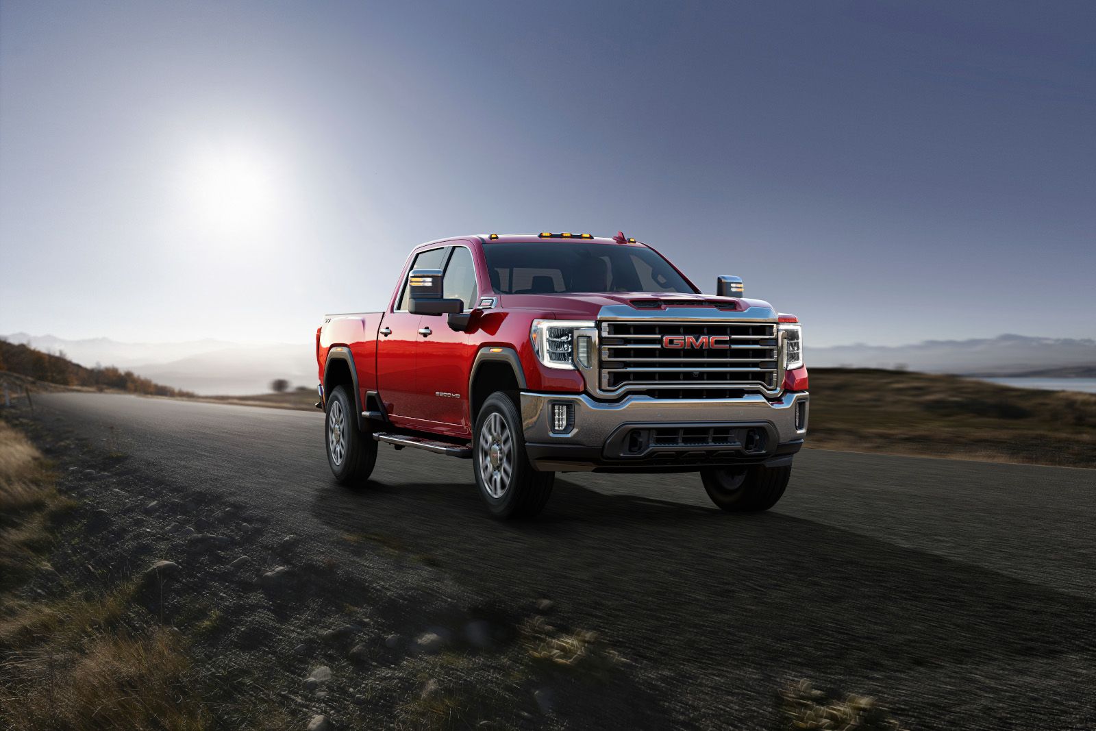 GMC Sierra 2500HD - front view of a red GMC Sierra 2500HD driving on a paved road at sunset - Autopark Brampton - Used car dealership in Brampton, Ontario