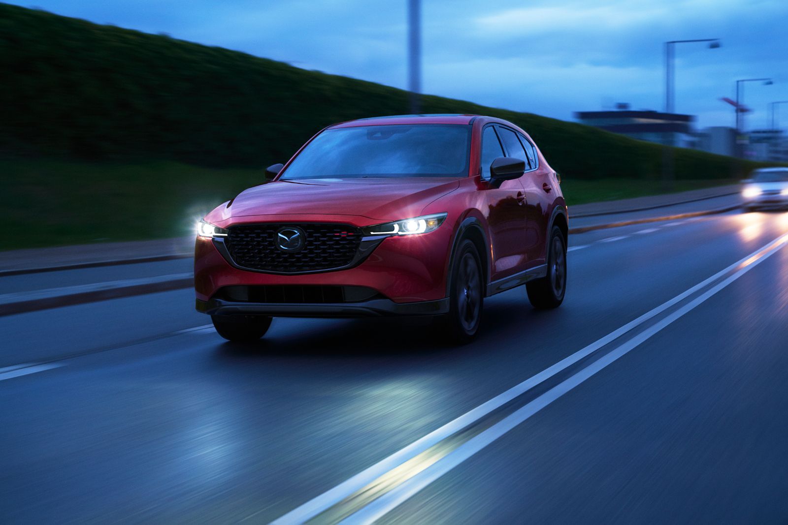 Mazda CX-5 - A red Mazda CX-5 driving on a highway at night with its headlights on - Autopark Barrie - Used car dealership in Barrie, Ontario