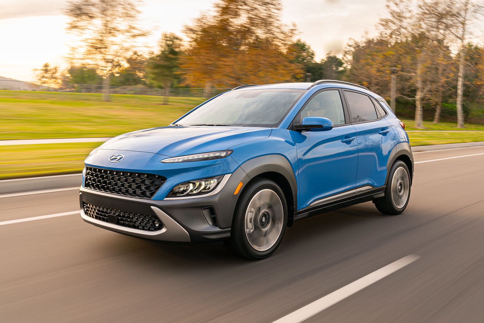 Hyundai Kona - A blue Hyundai Kona driving on a road at sunset - Autopark Barrie - Used car dealership in Barrie, Ontario