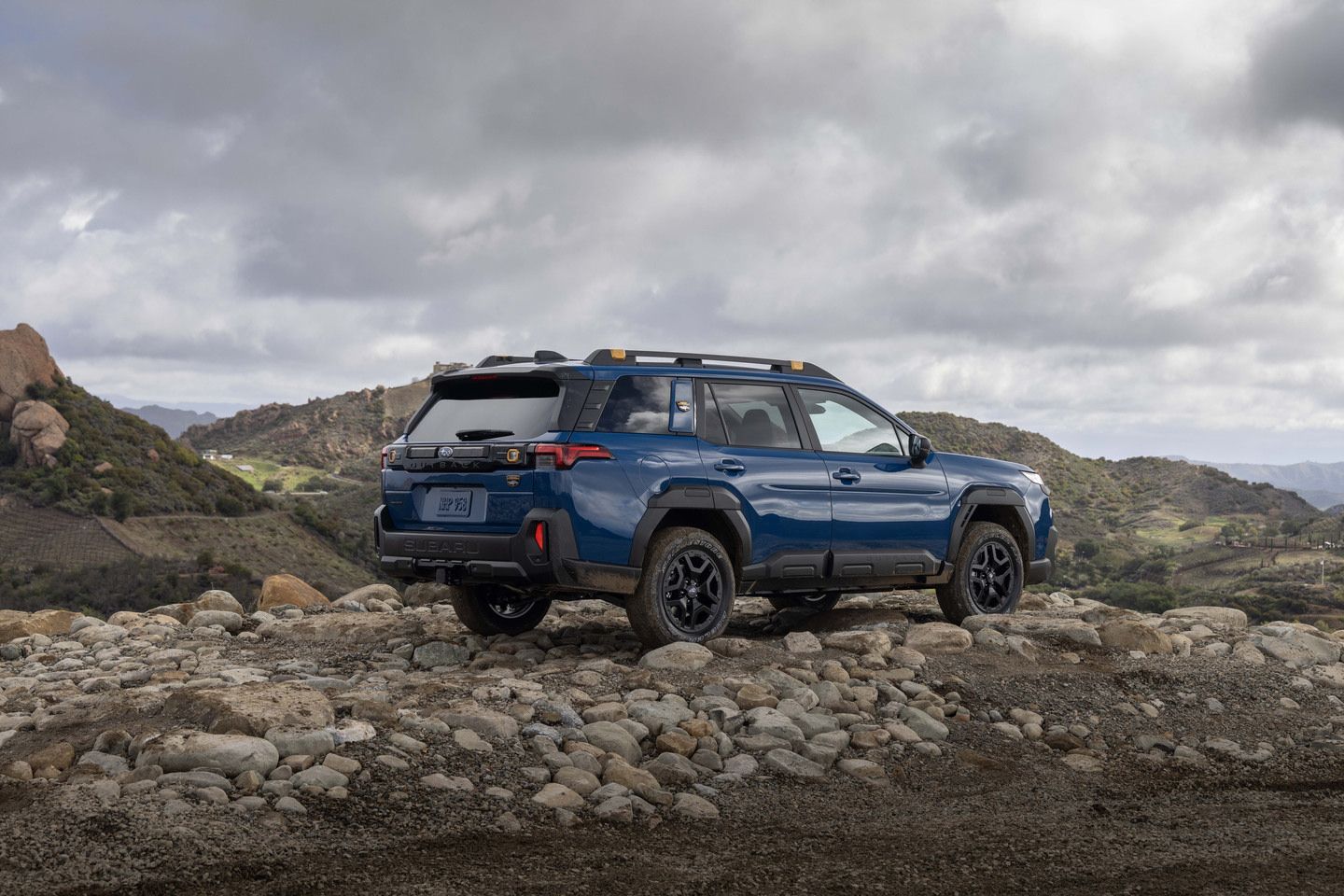 2026 Subaru Outback - Rear view of a blue 2026 Subaru Outback on a rocky overlook with mountains in the background - Humberview Group - Subaru car dealership in Ontario