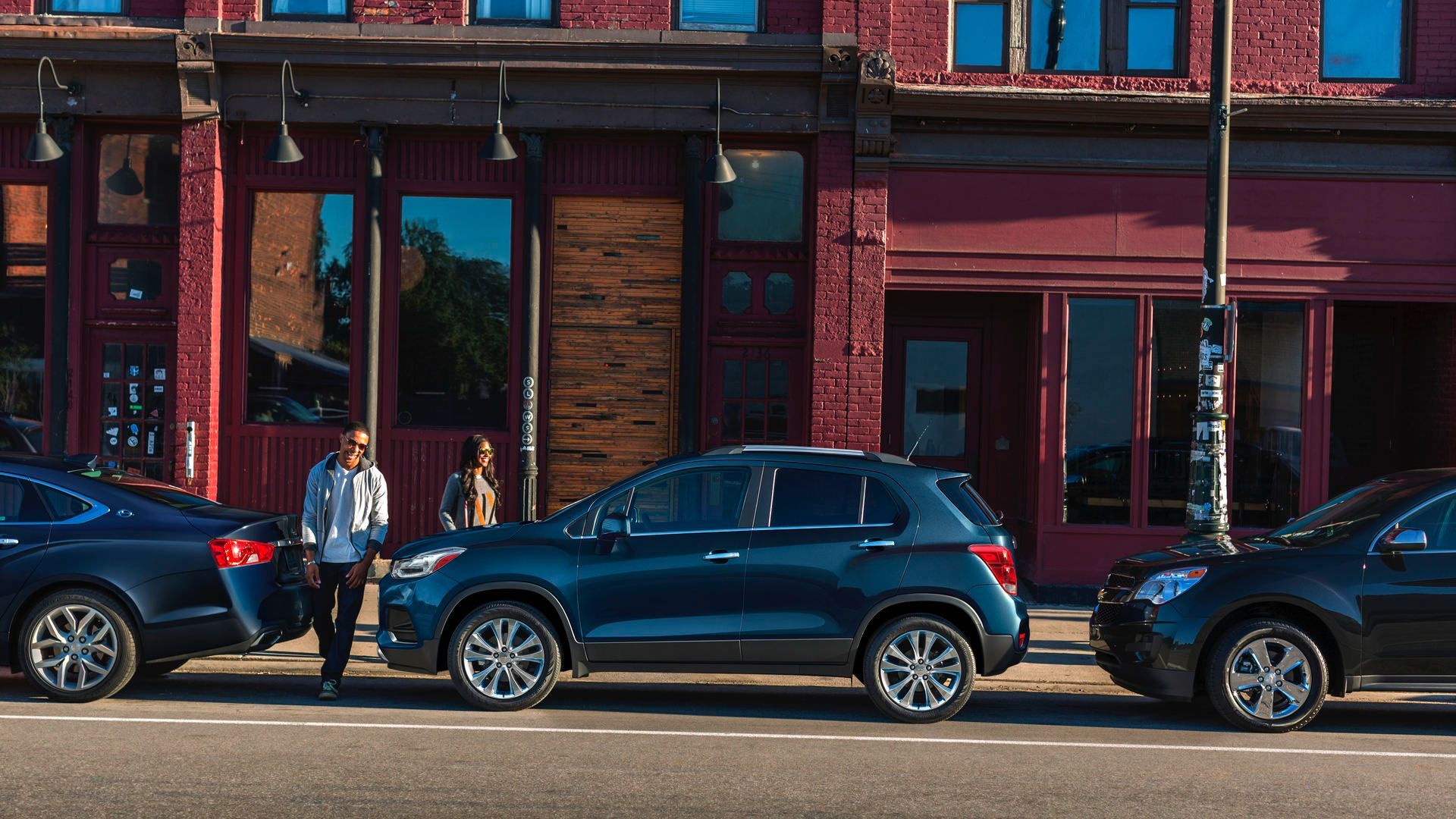 Chevrolet Trax - A dark blue Chevrolet Trax parallel parked on a main street in a city, shown in a side profile view - AutoPark Barrie - Used car dealership in Barrie, Ontario