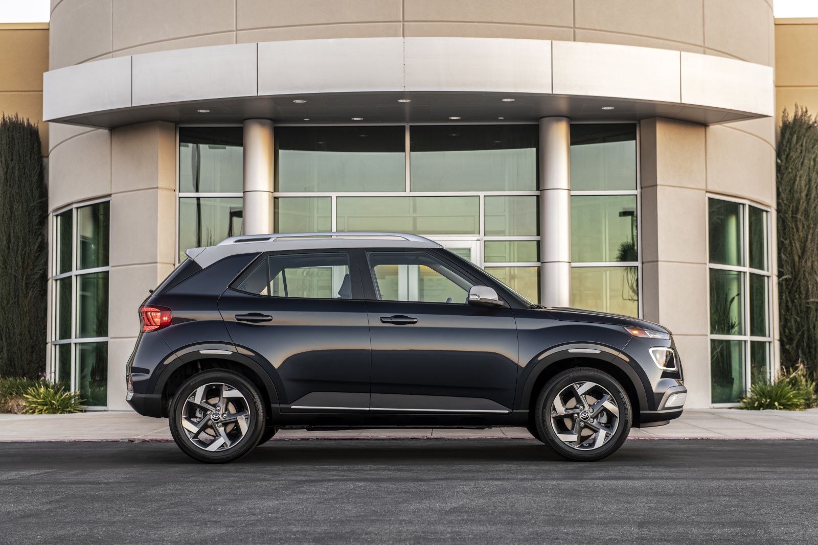 Hyundai Venue - A dark grey Hyundai Venue shown in a side profile, parked in front of a modern office building - AutoPark Barrie - Used car dealership in Barrie, Ontario