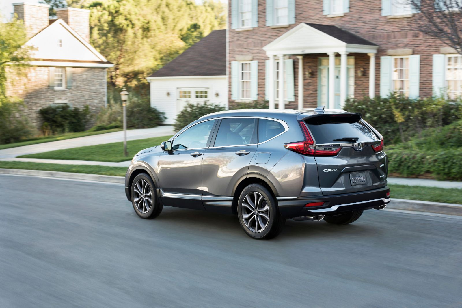 Honda CR-V - A grey Honda CR-V driving past suburban houses, shown from the rear-three-quarter angle - AutoPark Brampton - Used car dealership in Brampton, Ontario