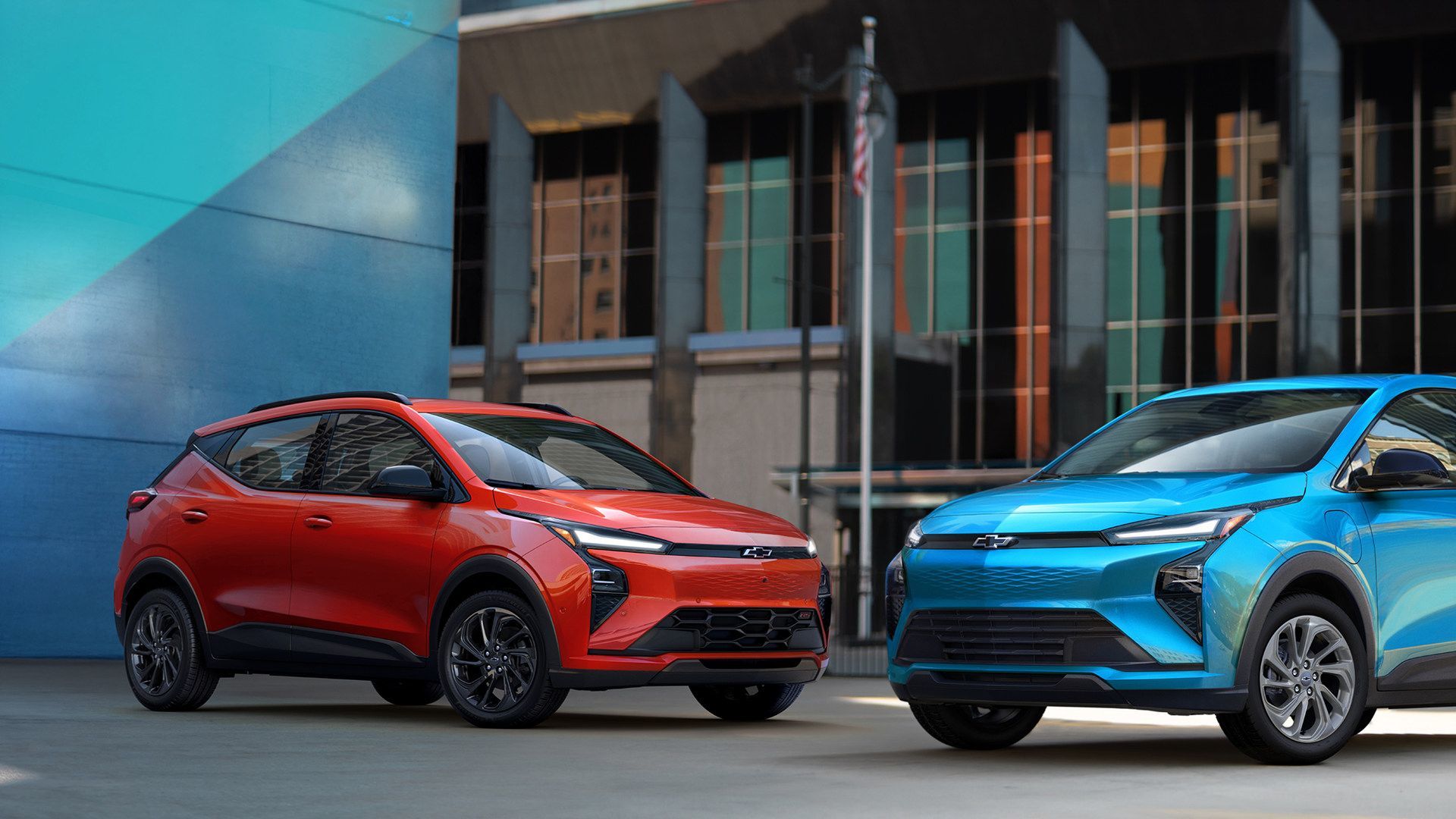 2027 Chevrolet Bolt - A red and a blue Chevrolet Bolt parked side-by-side in a city.